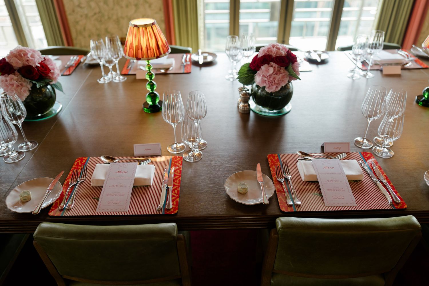 Elegant wedding reception table set with pink floral centerpieces, crystal glasses, and menus.