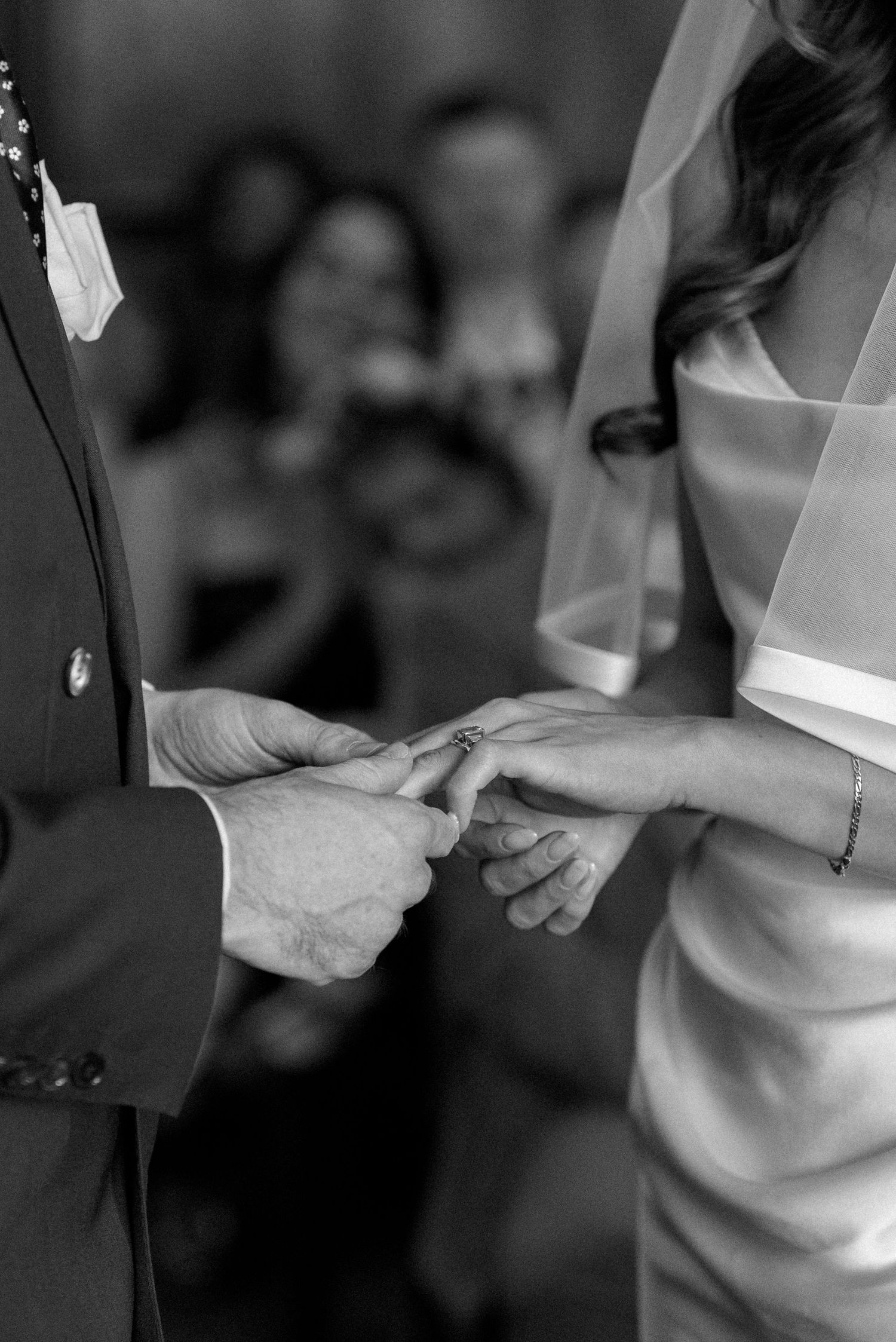 Groom places a wedding ring on the brides finger during an intimate ring exchange ceremony in black and white.