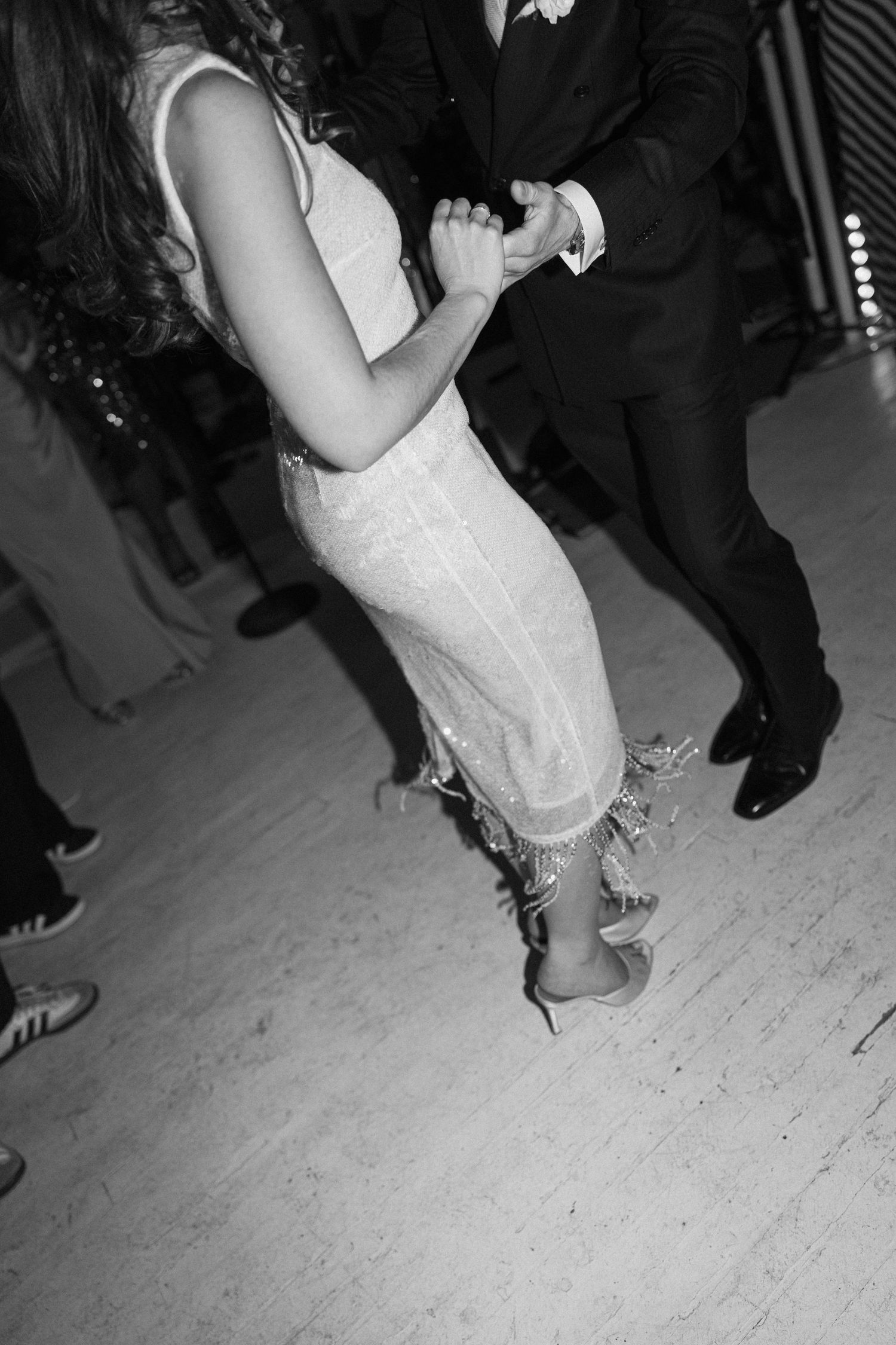 Black and white close-up of bride and groom dancing together on wedding reception dance floor.