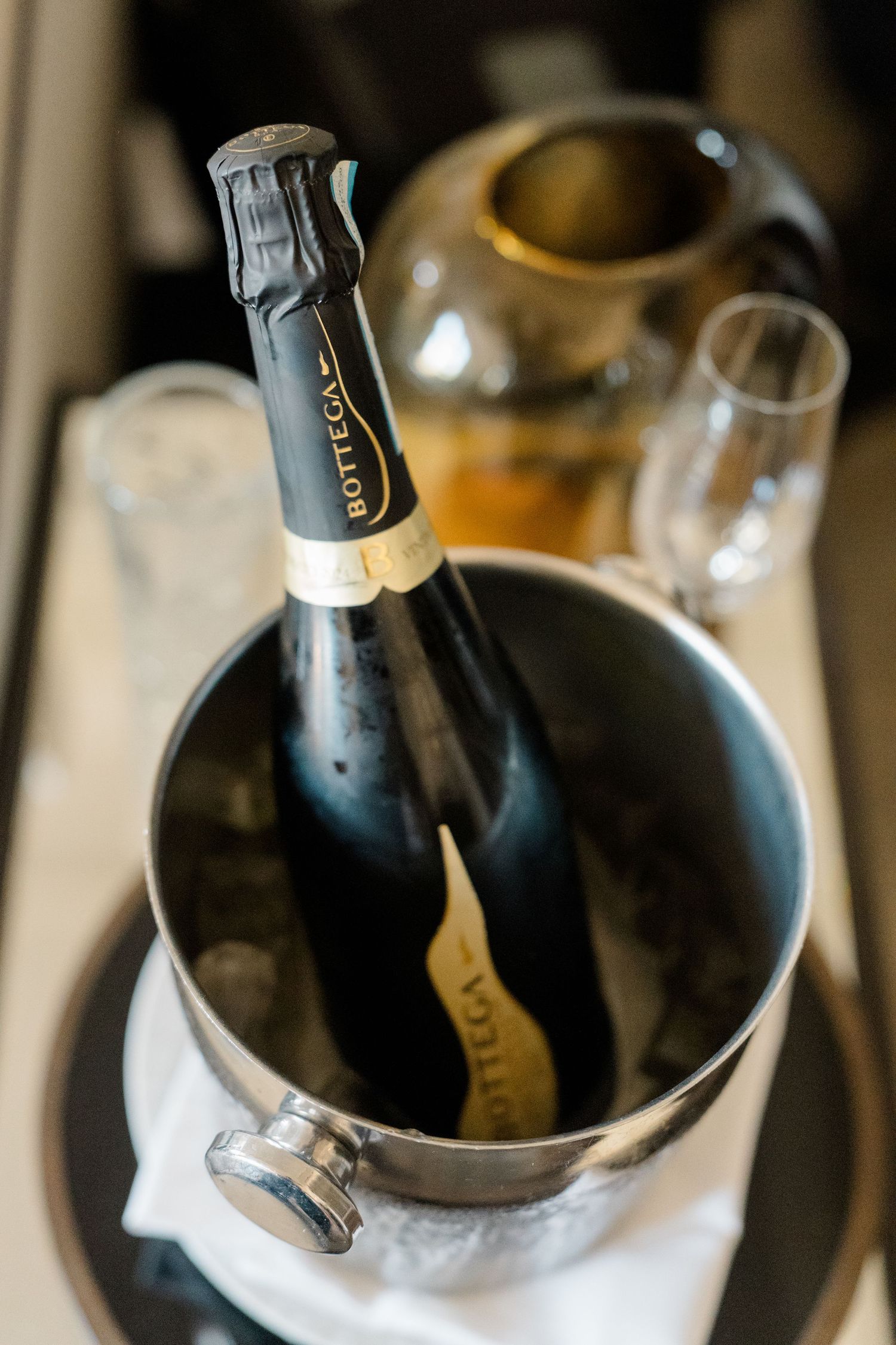Bottega sparkling wine chilling in ice bucket on wedding day preparation tray.