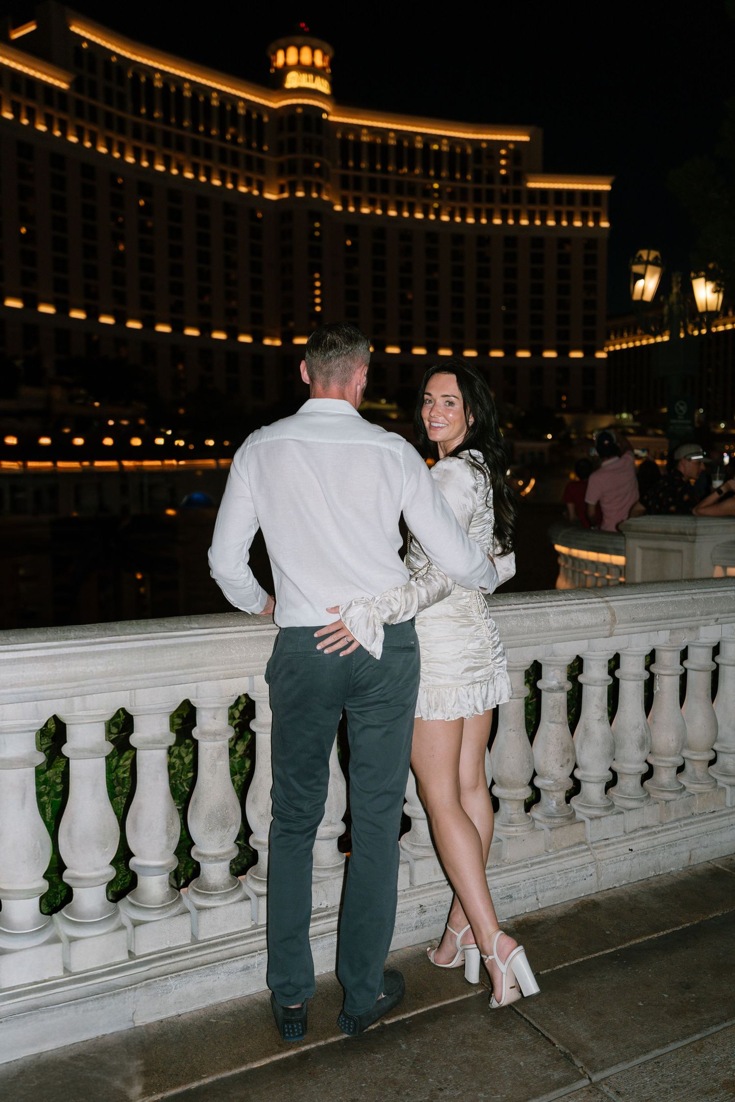 A couple shares an intimate moment along the Bellagio's balustrade at night.