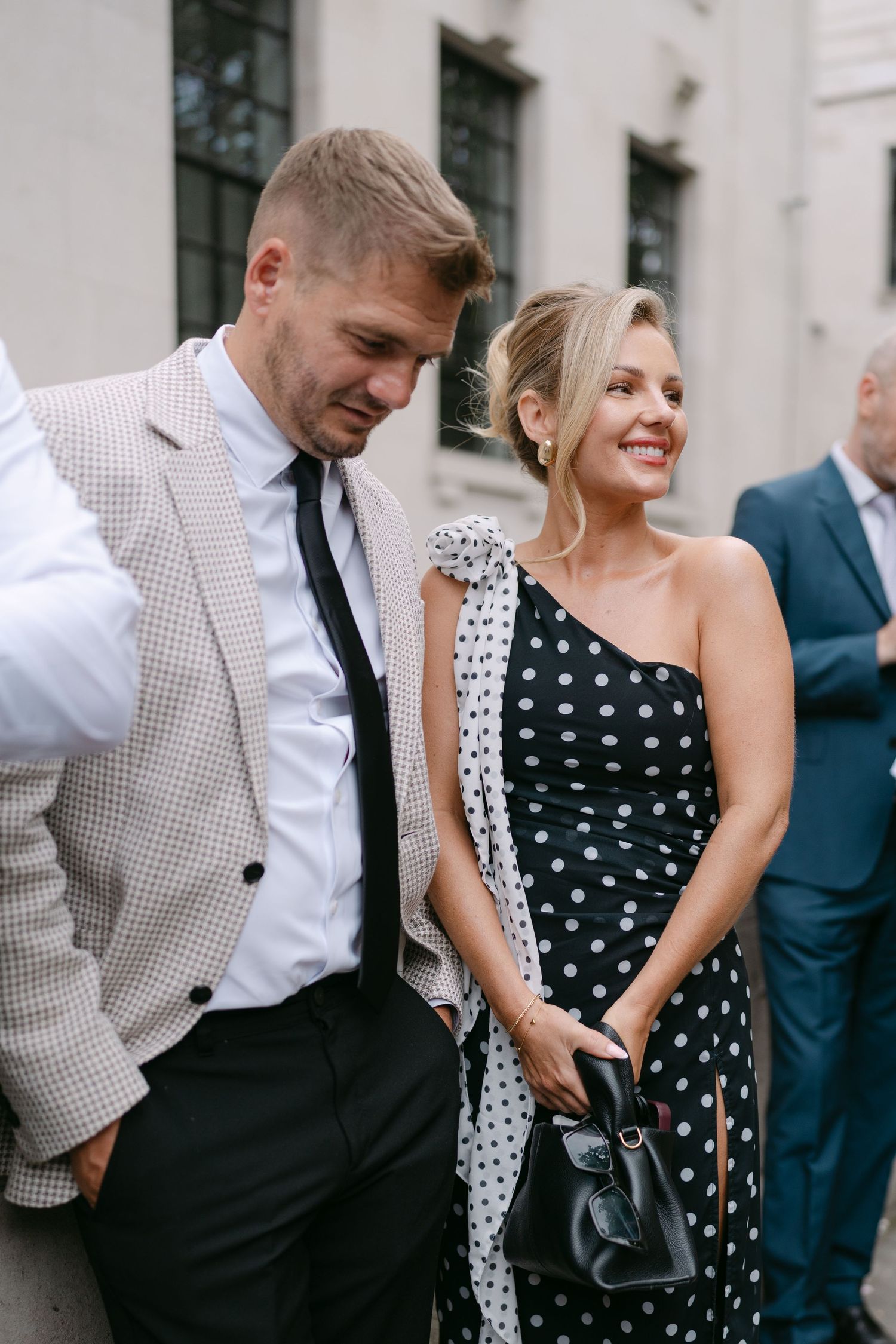 Wedding guests in polka dot dresses and formal wear share joyful moments at an outdoor reception.