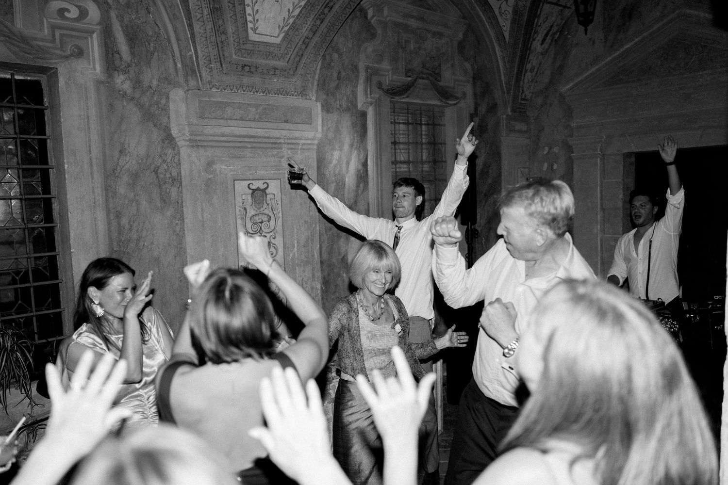 Black and white shots of people dancing with hands raised at a celebration.