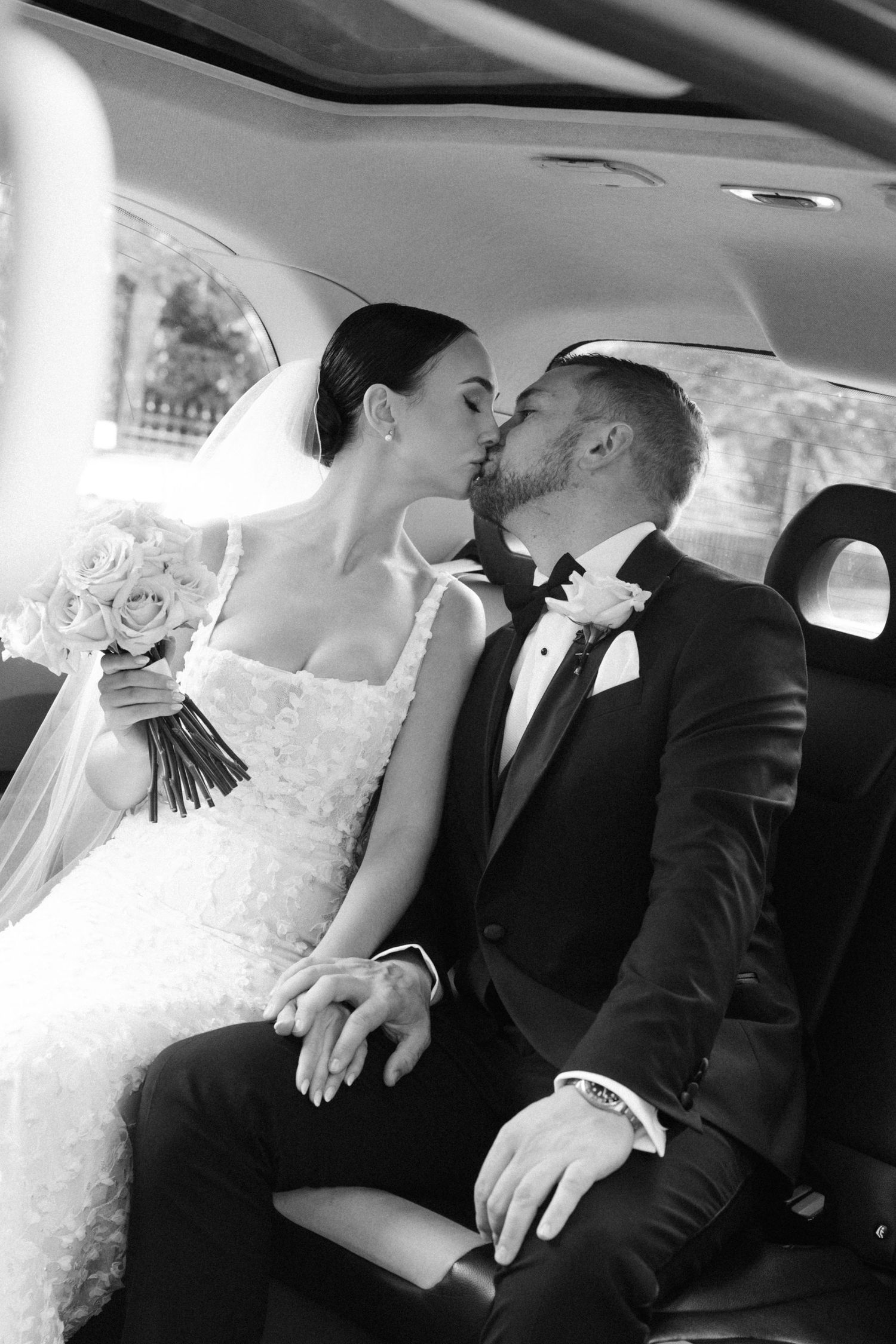 Intimate black and white wedding photo captured inside a luxury car interior.