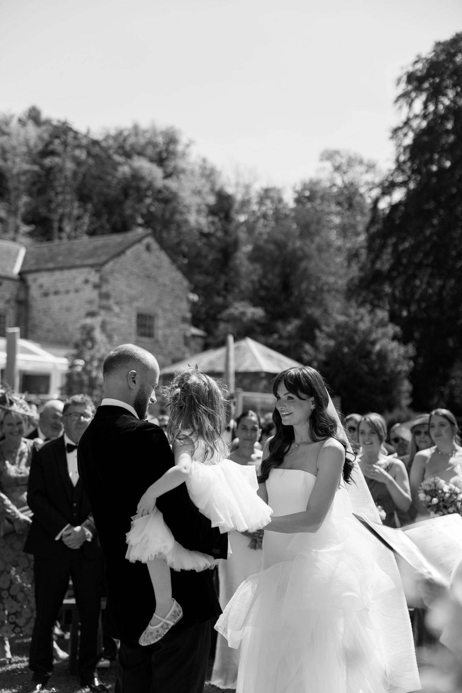 Black and white photo of wedding guests dancing and celebrating outdoors.