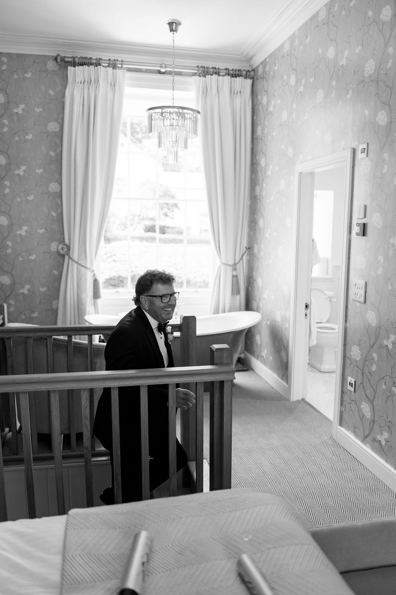 Black and white photos showing a hallway with decorative wallpaper and wooden railings.