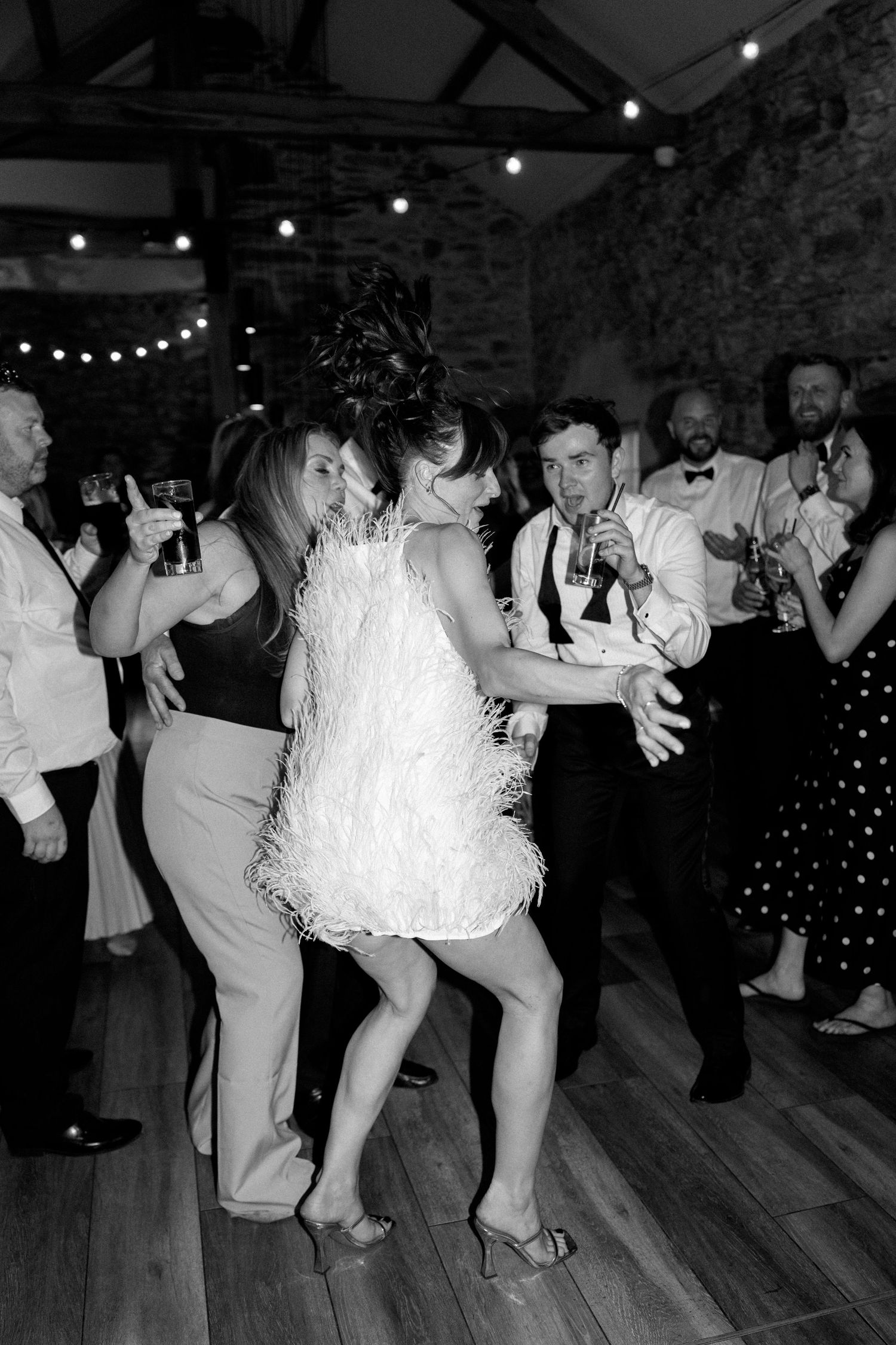 Dynamic dance moves captured in black and white on a wooden dance floor at an elegant event.