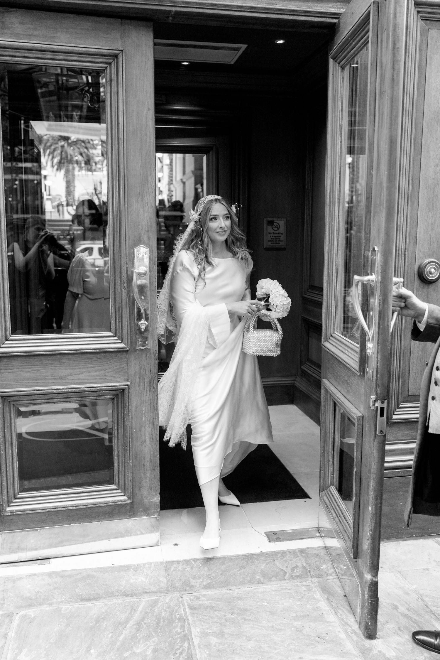 Black and white sequence of someone in white clothing pushing through revolving doors at an entrance.