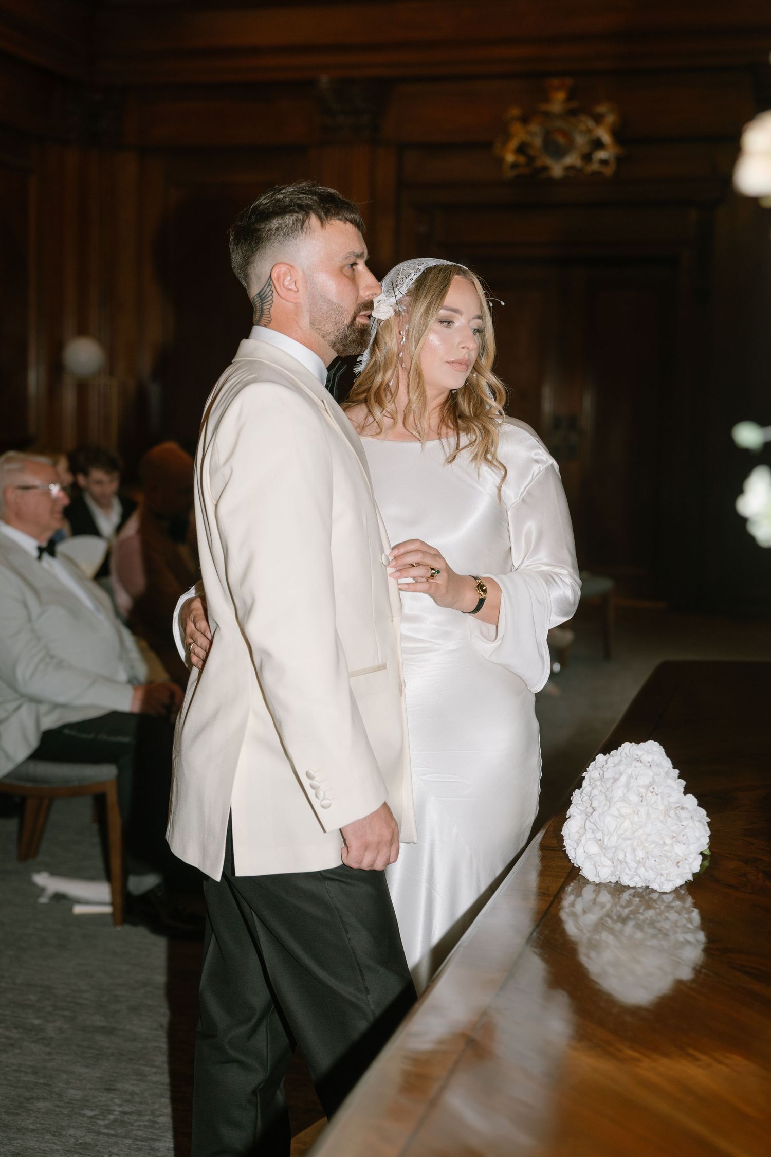 A couple dances together during their wedding reception in a dimly lit ballroom.
