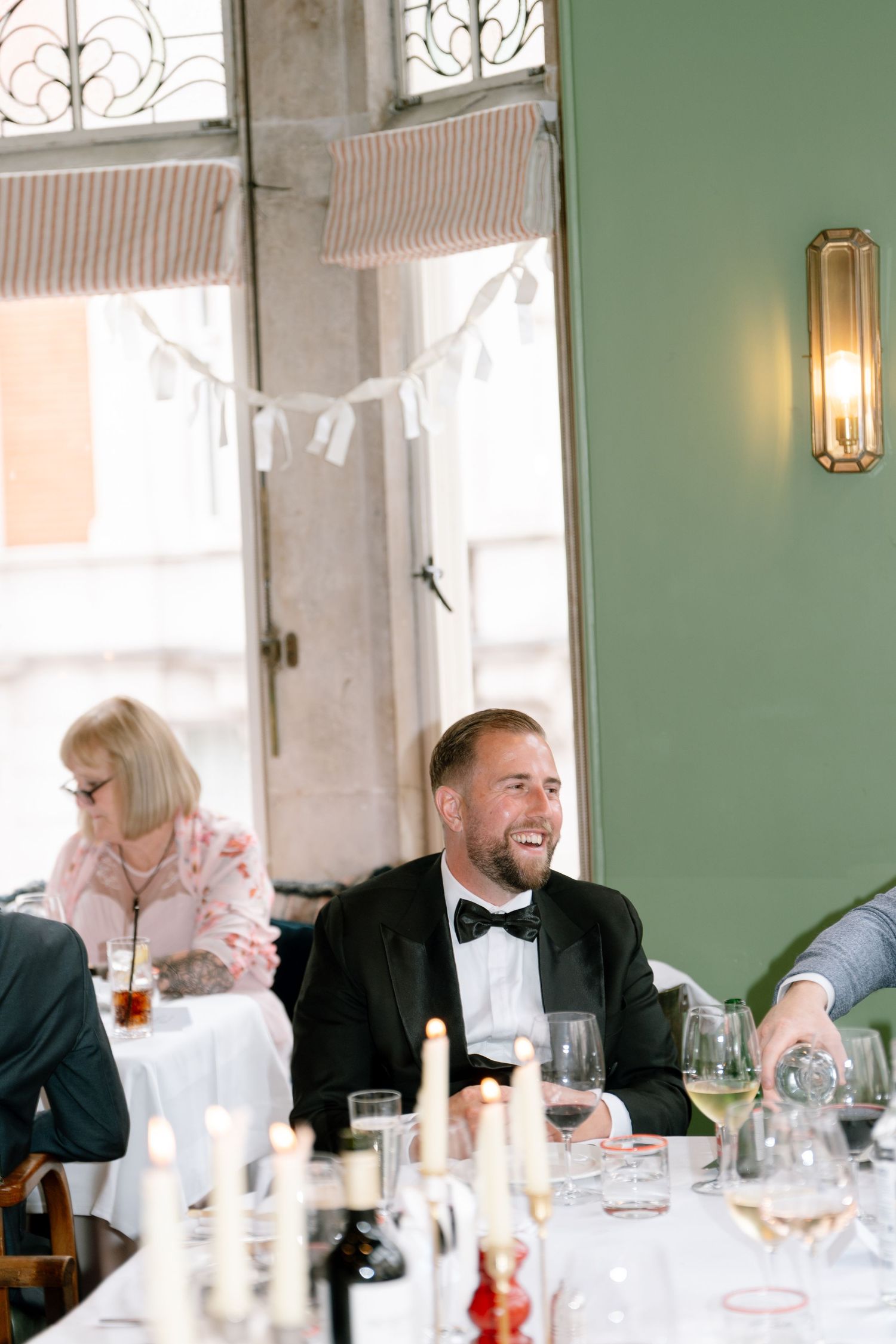 Wedding reception guests enjoying conversation at elegant table with candles and wine glasses.