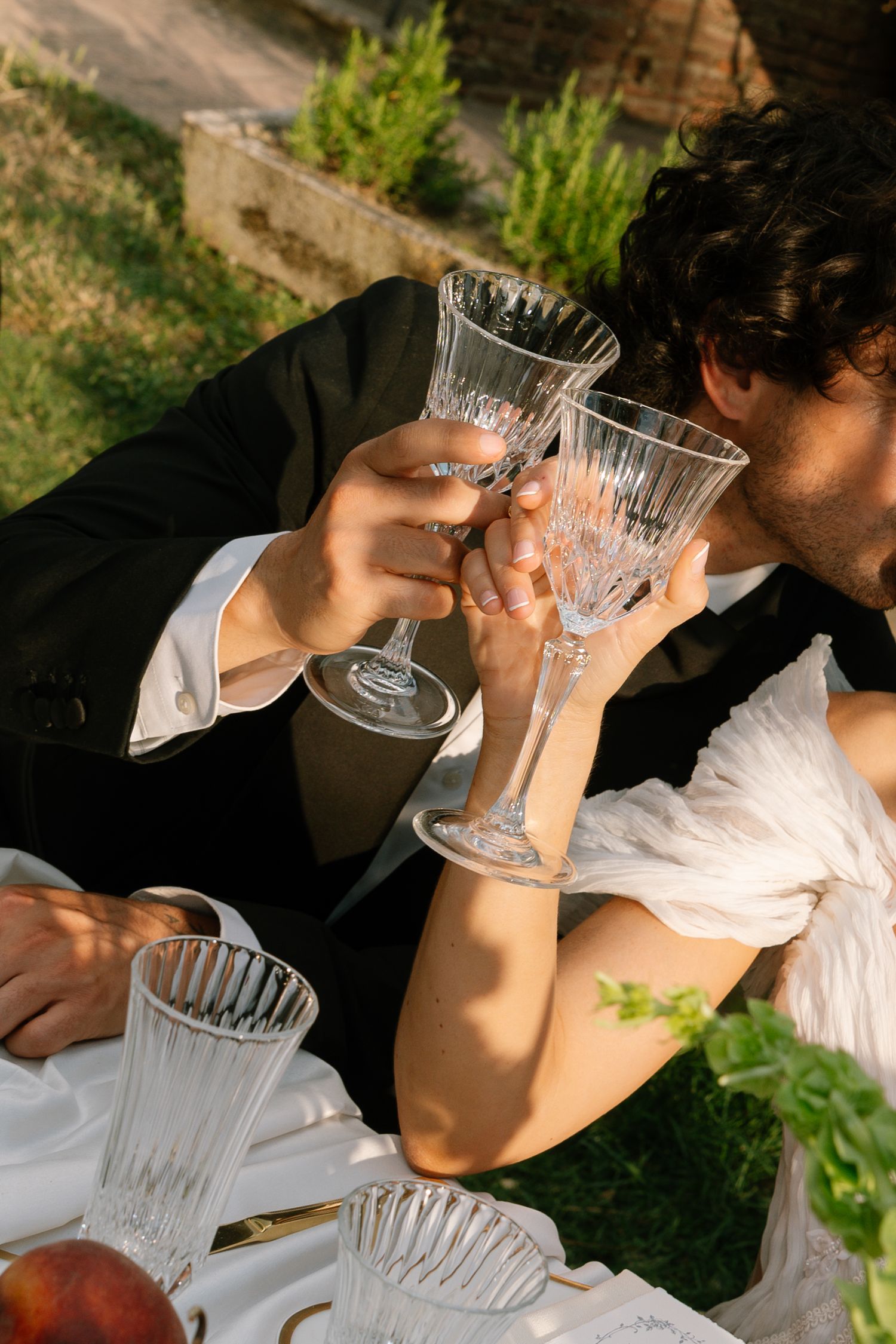 A series of images showing someone drinking from crystal glasses in an outdoor garden setting.