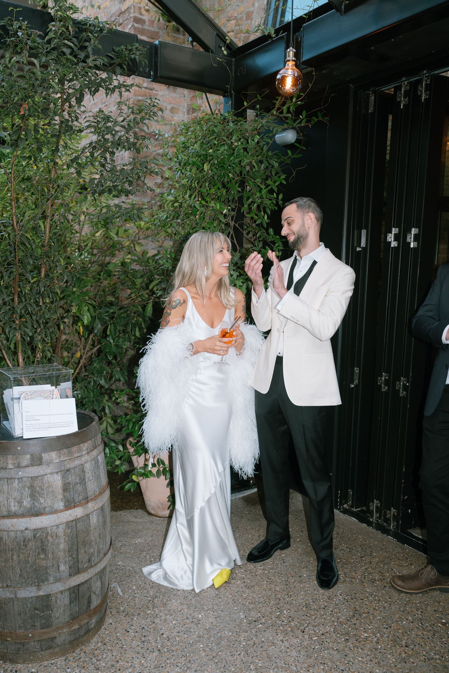 Couple dancing and laughing together near wooden barrels at an evening event.