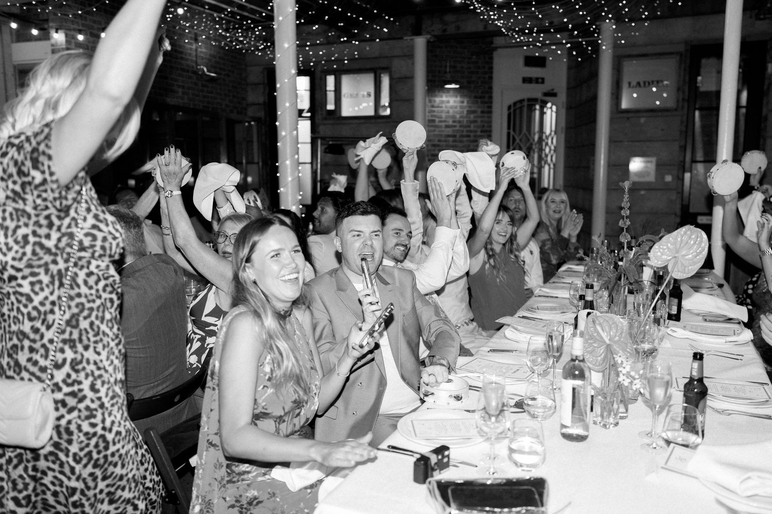 Wedding reception guests seated at long tables with elegant place settings and decorations.