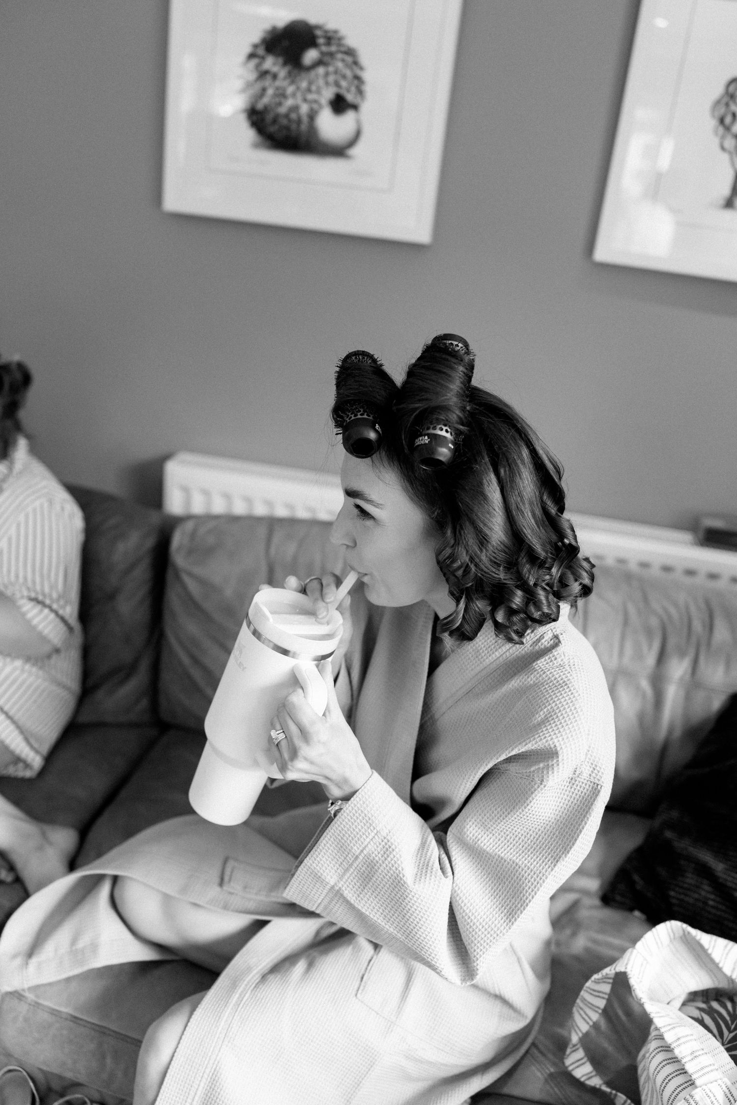 A person in white robe relaxing on a couch during wedding preparations.