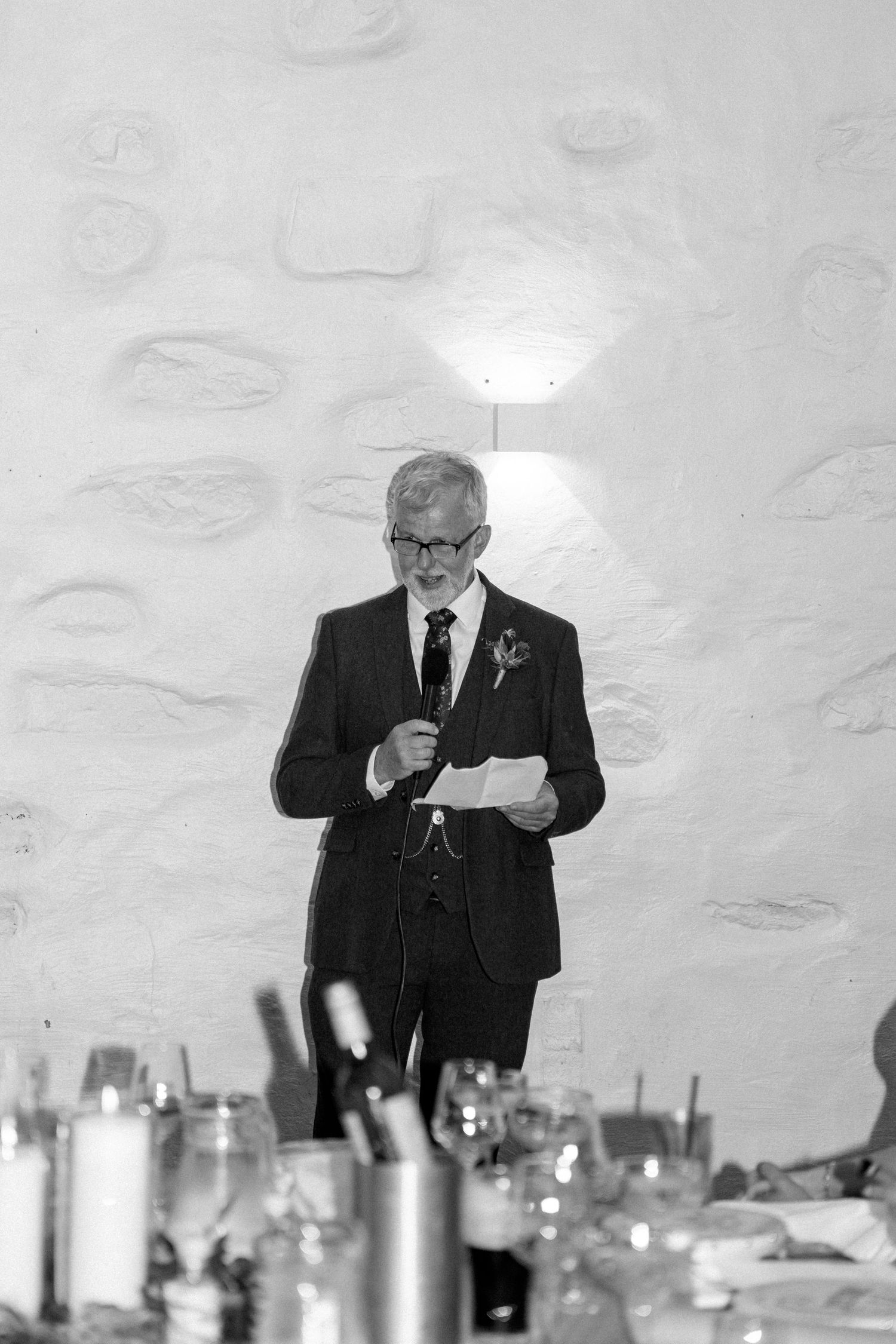 A speaker gives a speech at an elegant dinner reception with candles on the table.