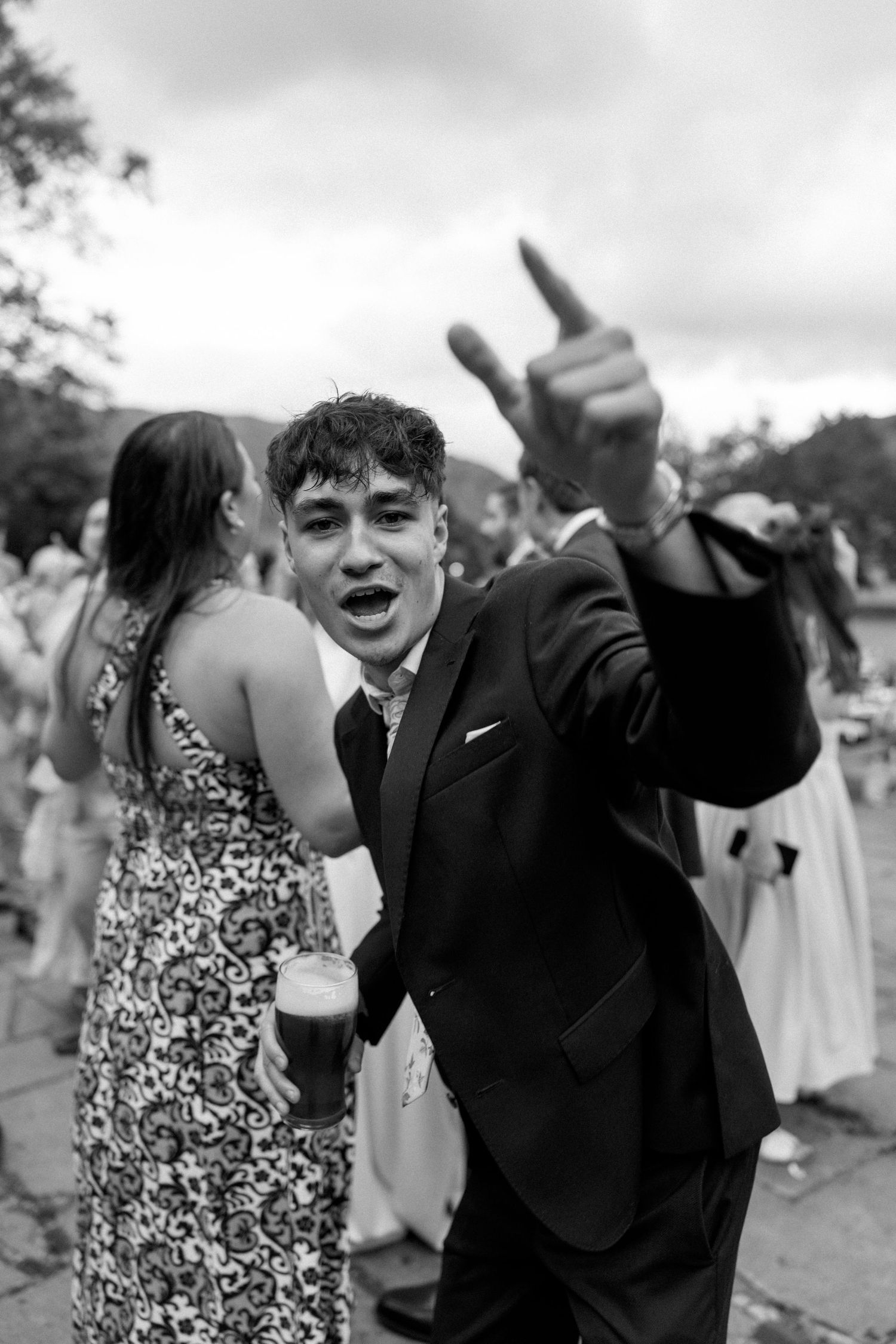 Wedding guests dancing and celebrating enthusiastically at outdoor reception.
