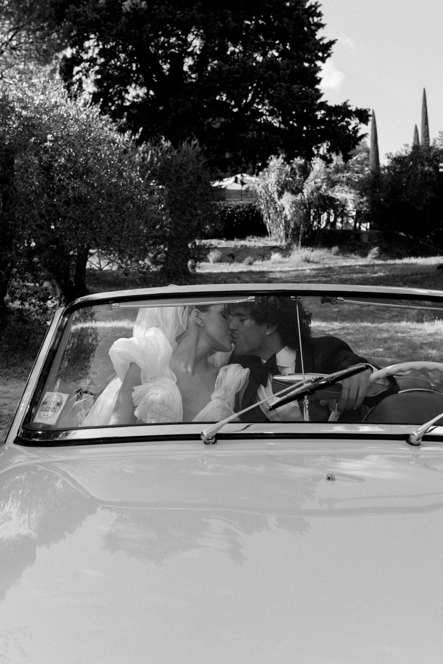 Black and white sequence showing occupants in a vintage convertible car.