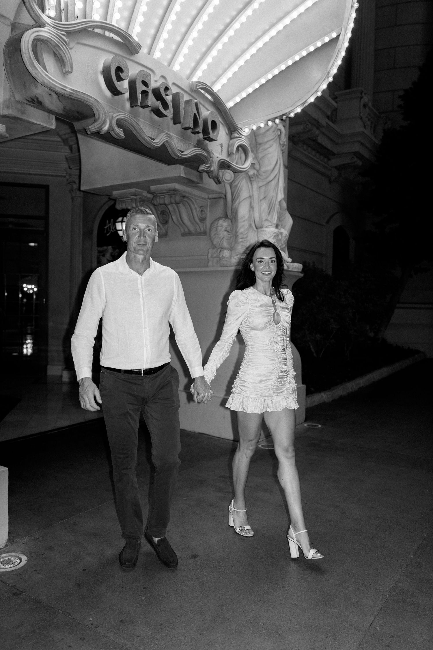 A couple poses under the vintage Caesars Palace sign in Las Vegas.