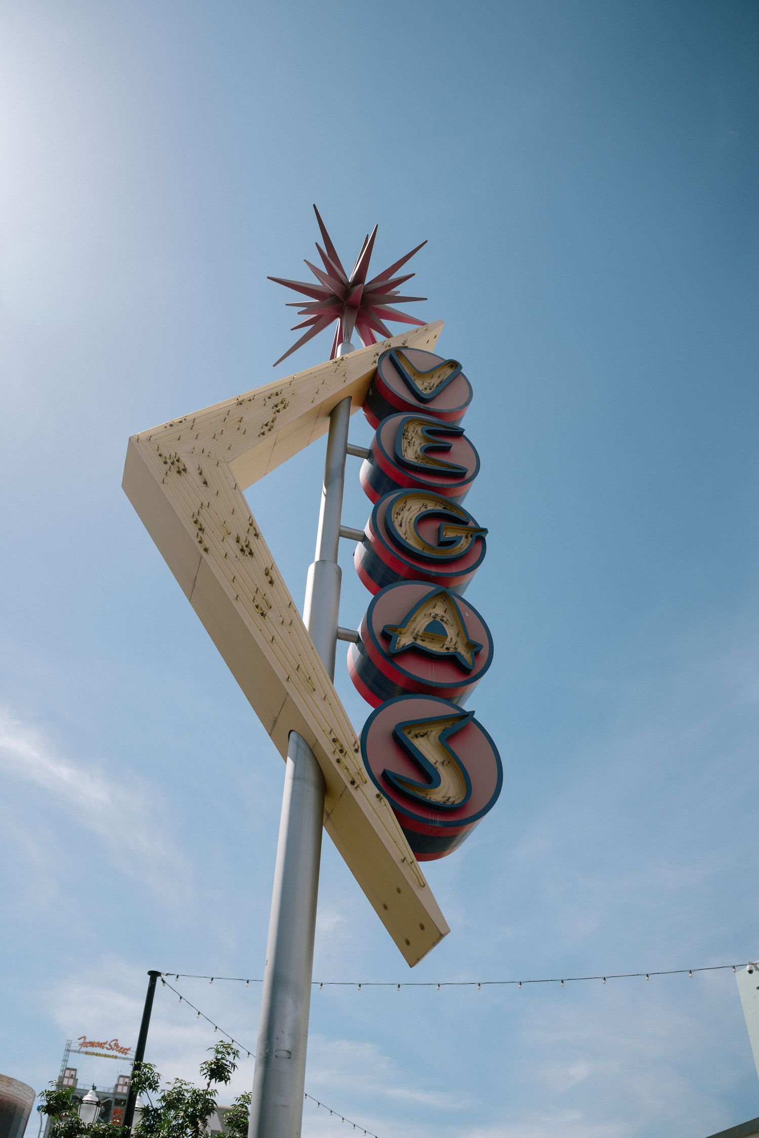 Retro neon sign with geometric shapes against bright blue sky.