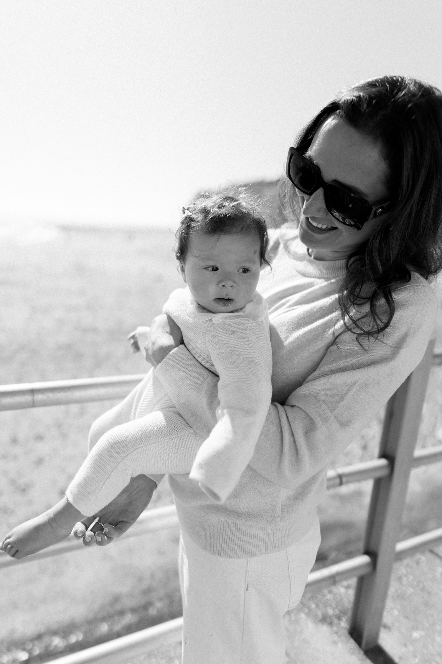 A tender moment between parent and baby wearing white outfits against a light background.