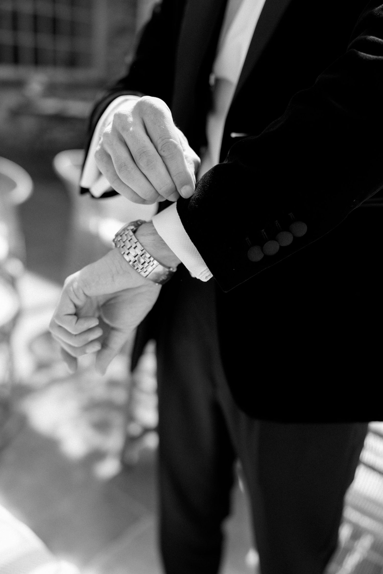 Close-up of hands in formal wear checking time on a wristwatch.