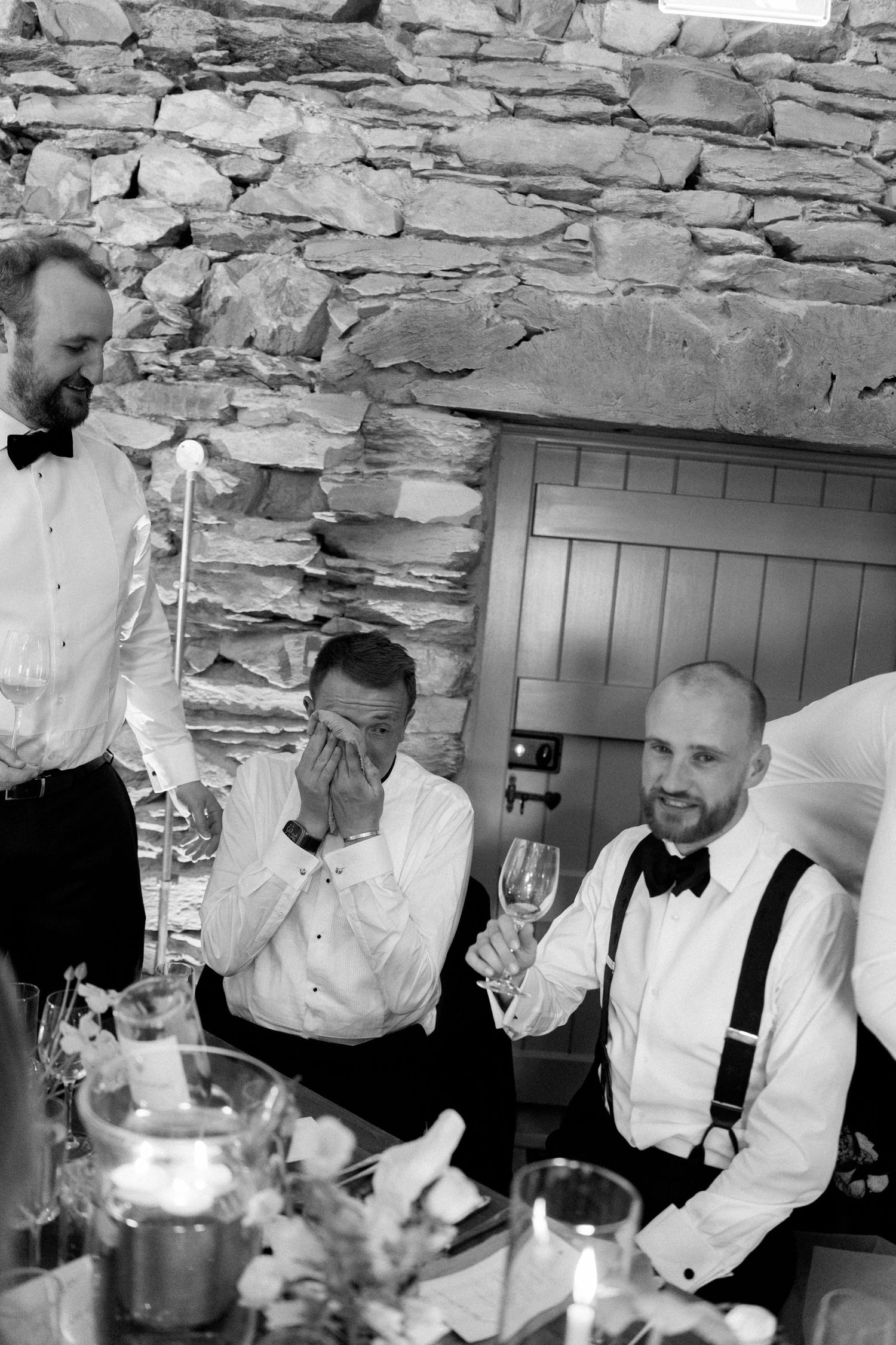 Wedding party members celebrating with drinks at an elegant stone-walled reception venue.