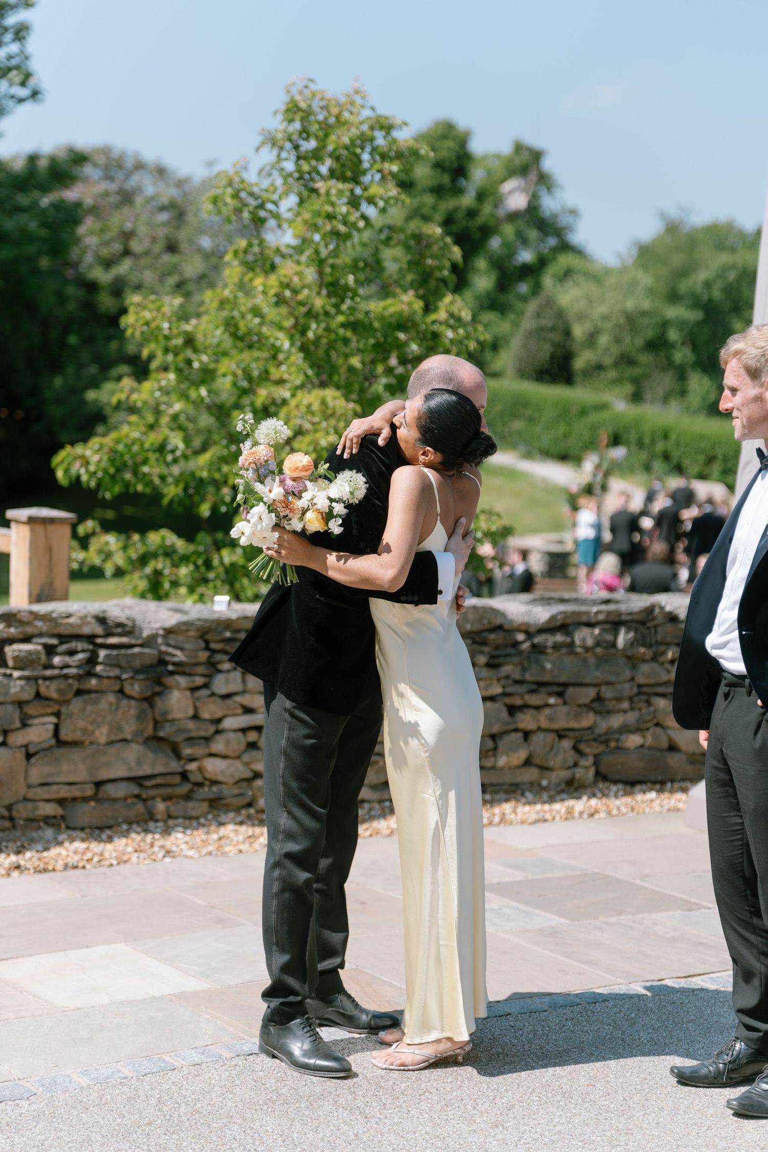 Wedding couple sharing a romantic moment against a rustic stone wall backdrop.