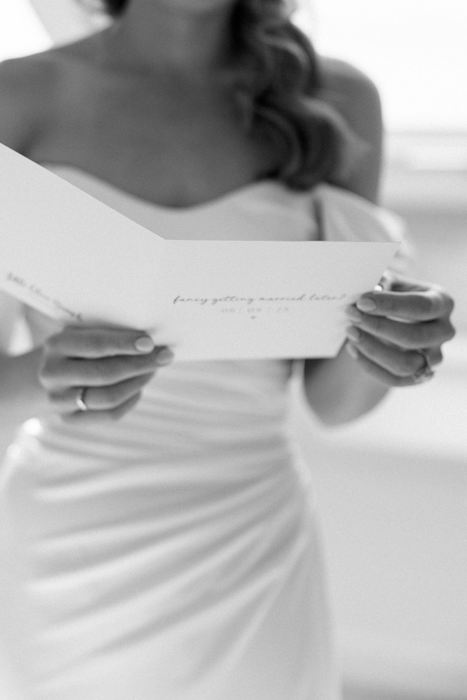 Close-up shots of hands holding wedding day note cards in white dress.