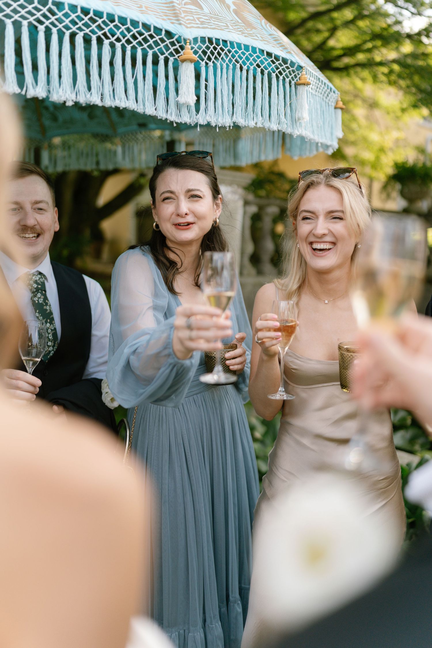 Wedding party celebrating under a decorative blue and white striped parasol.