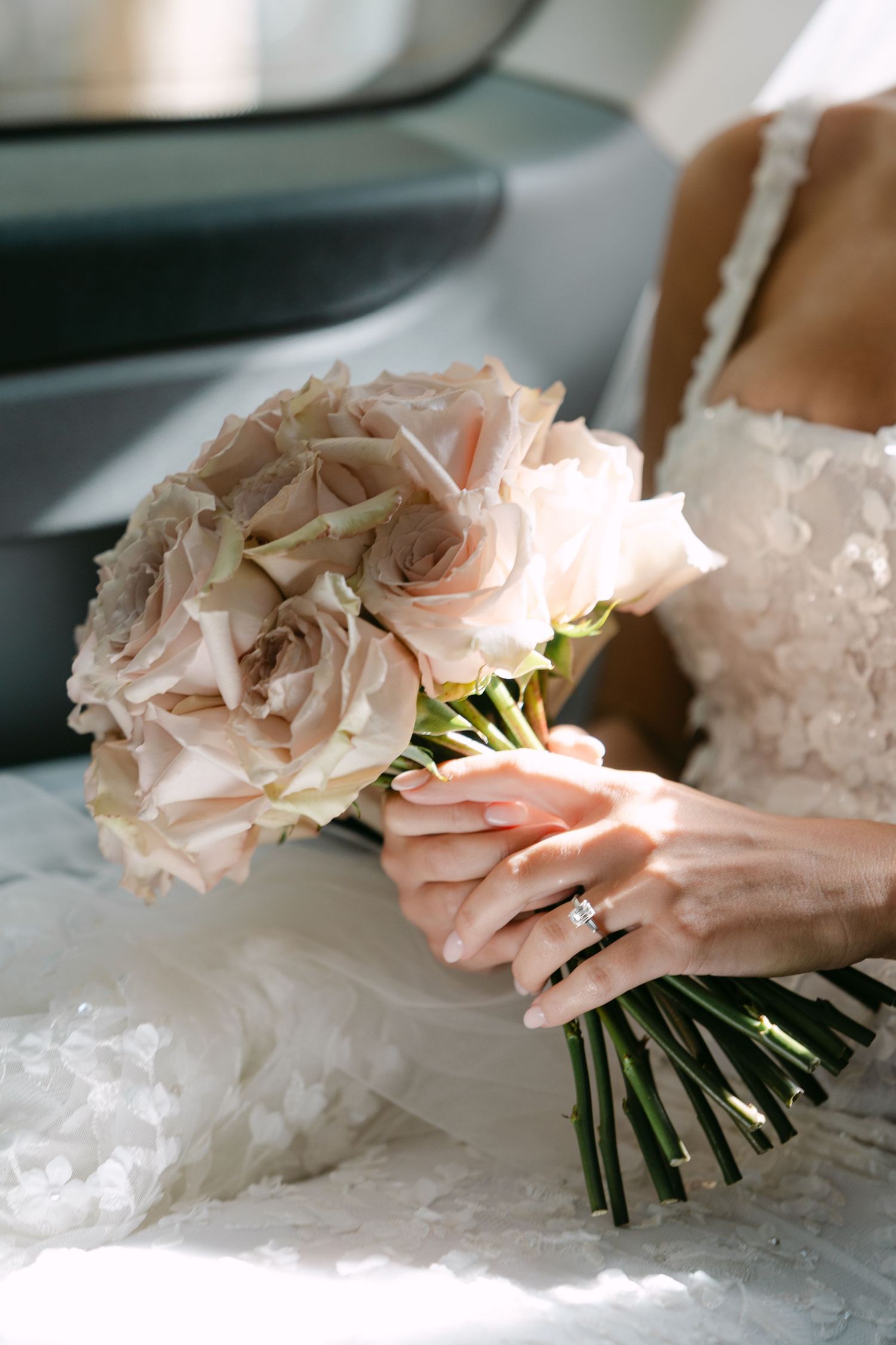Close-up of a delicate pink and white rose wedding bouquet held against a lace dress.