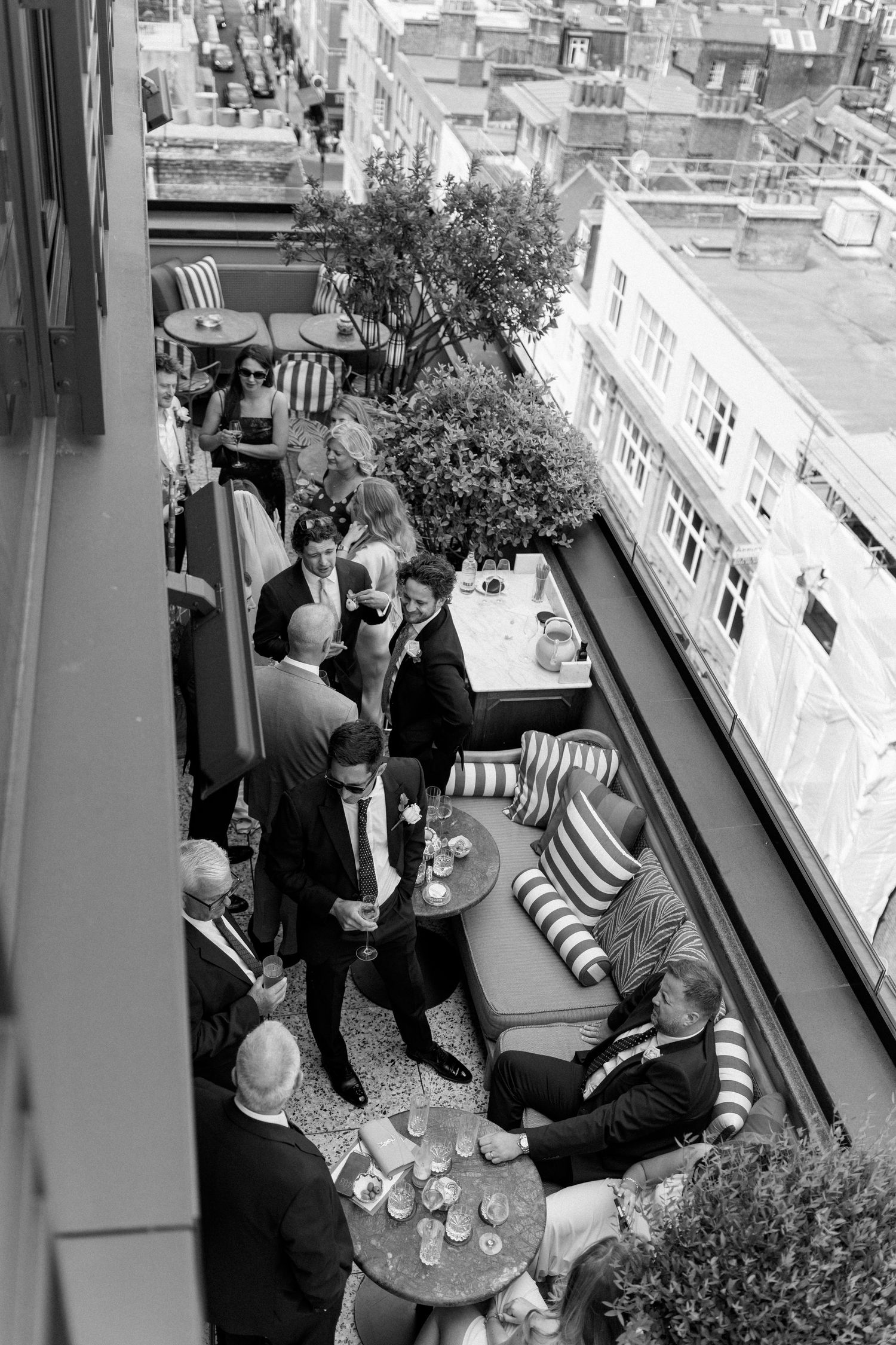 Aerial black and white view of wedding guests on rooftop terrace.