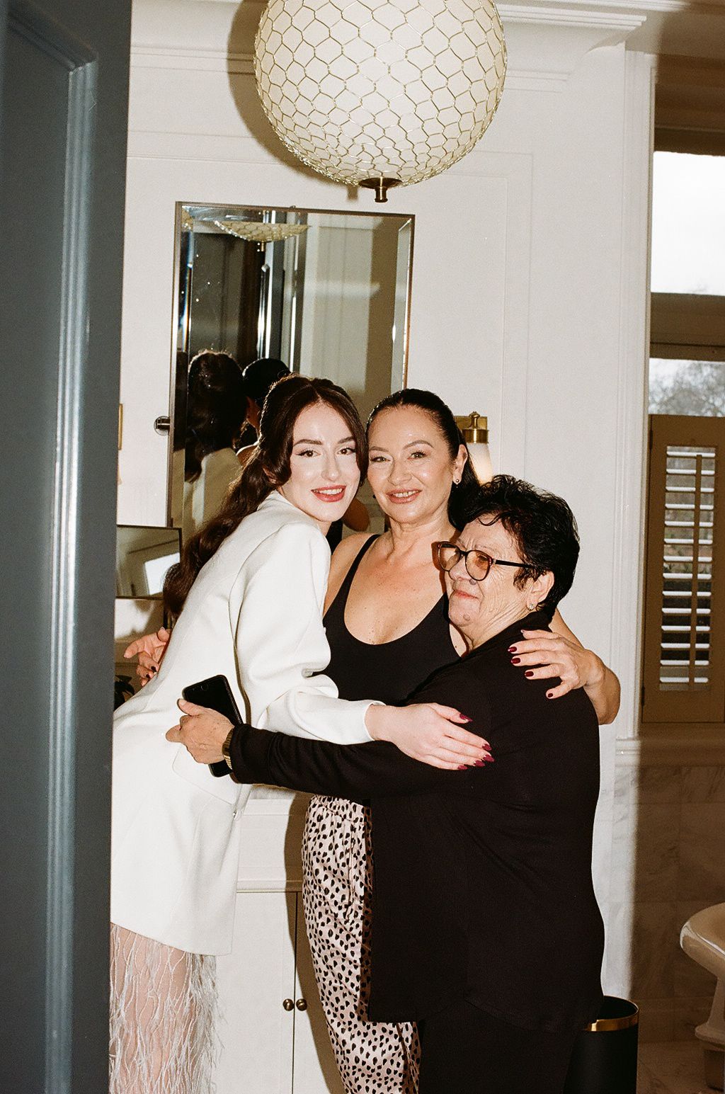 A group of people hugging and embracing in a hallway with white walls and paper lantern decorations.
