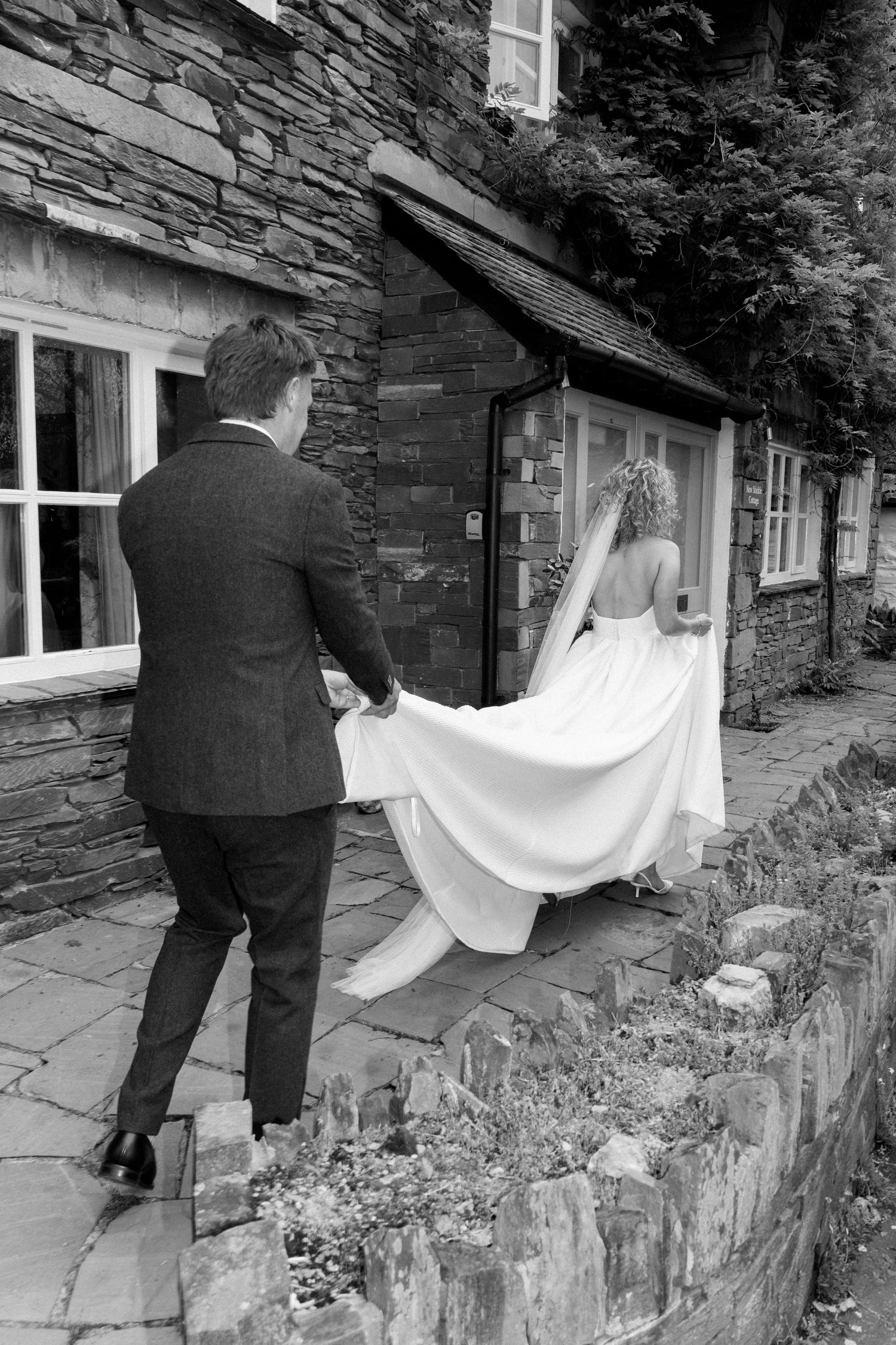 Wedding dress being passed through a window of a stone cottage in sequential shots.