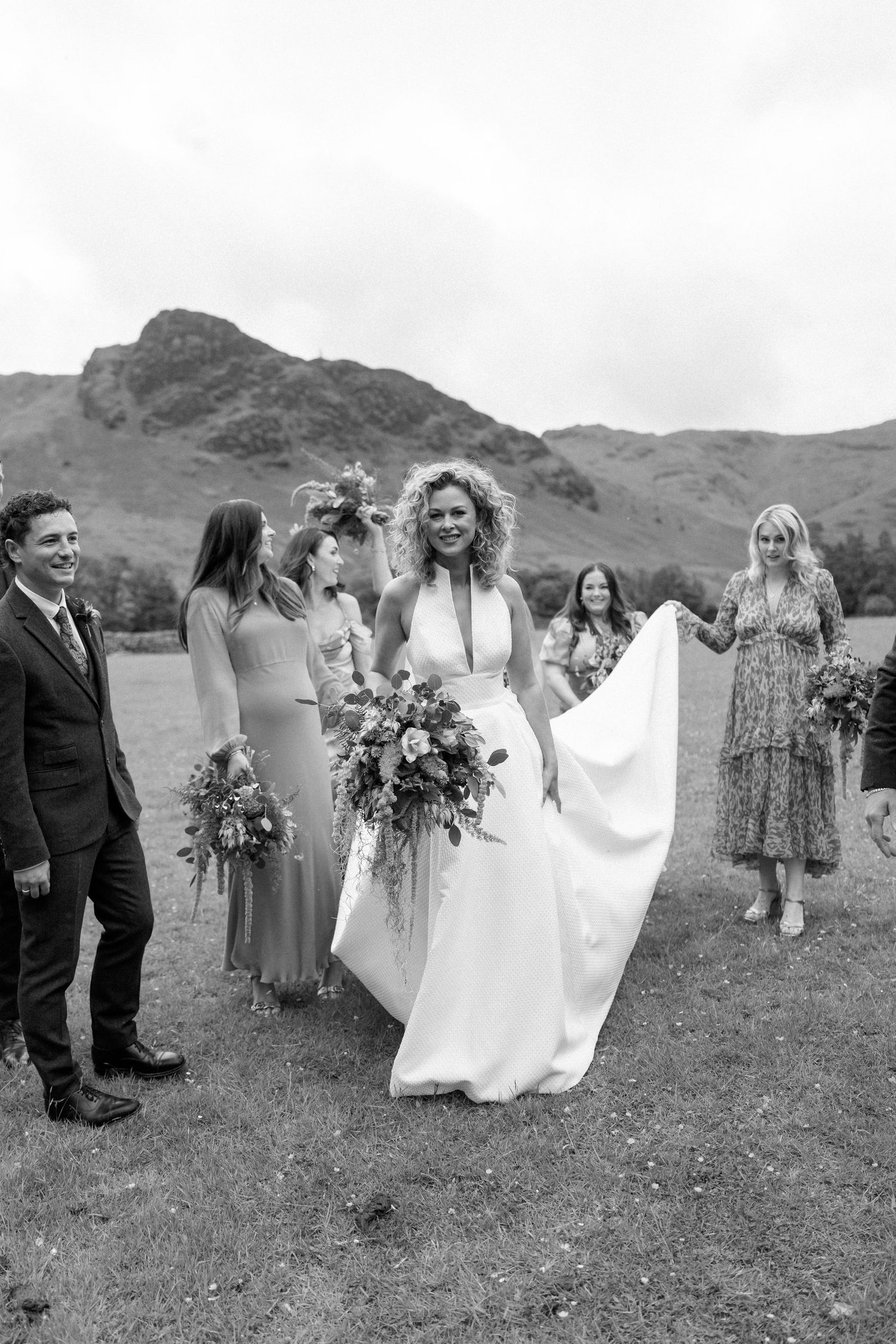 Wedding party gathered outdoors with mountain backdrop in black and white.