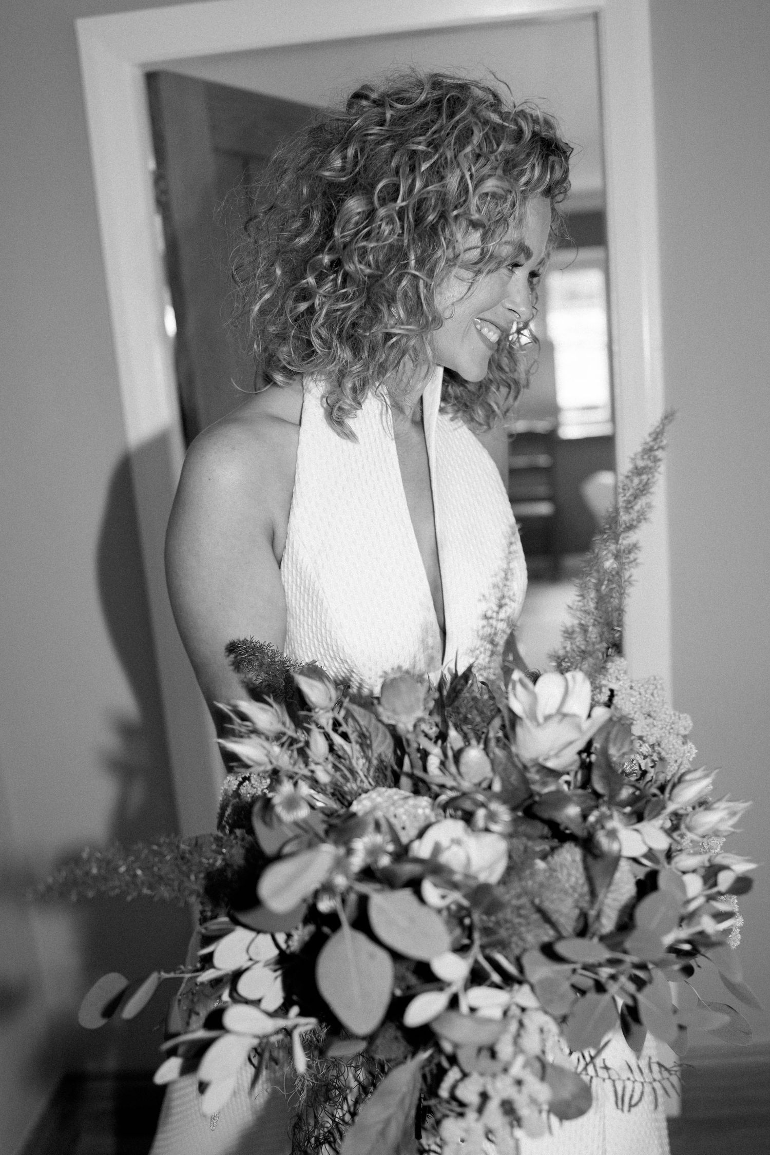 Black and white portrait showing a textured halter wedding dress and wild flower bouquet.