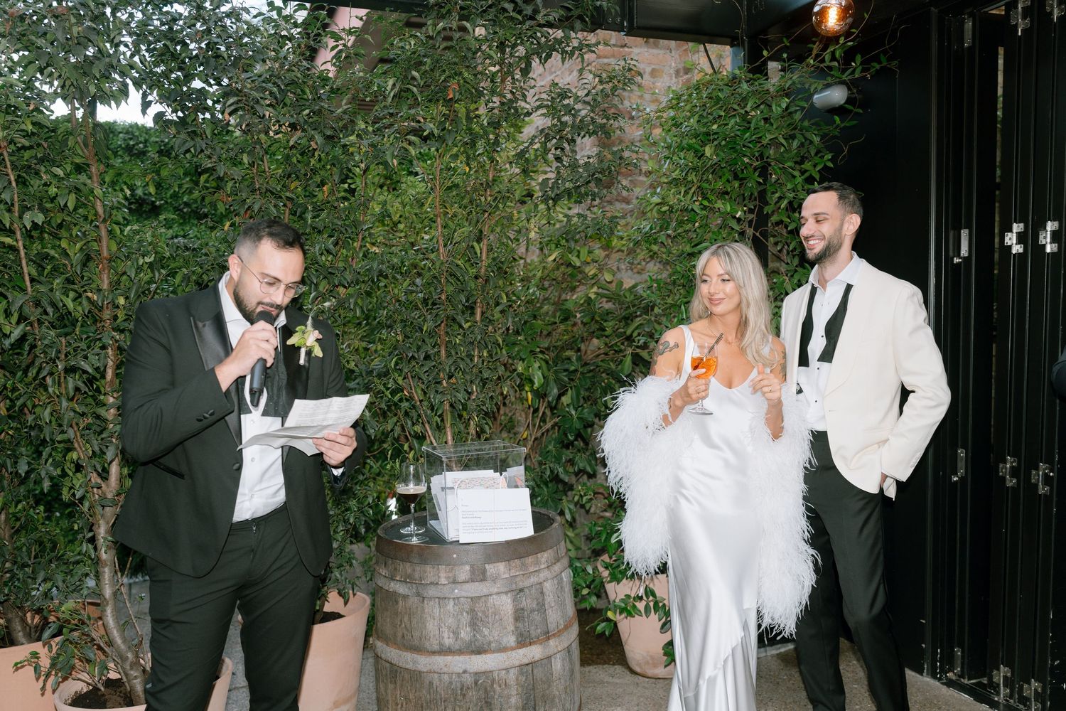 Wedding guests mingling outdoors in an evening garden setting with string lights.