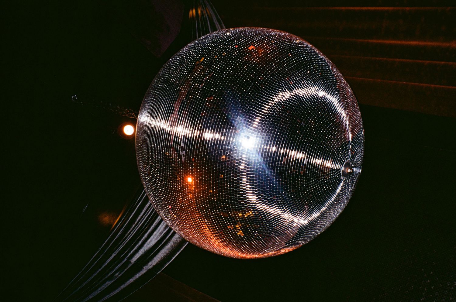 Glittering disco ball reflecting light patterns in a dark party space.