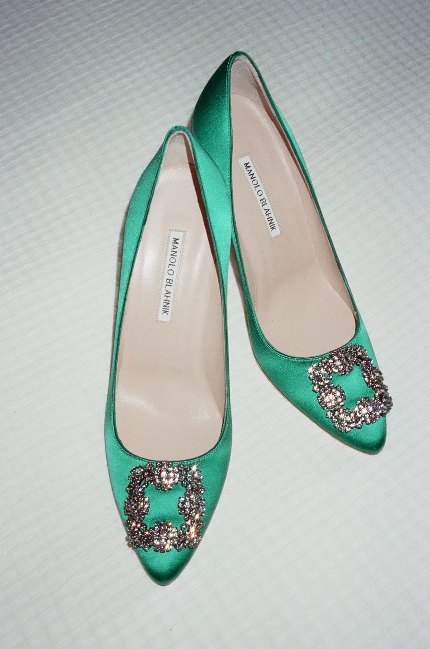 Elegant emerald green satin flats with ornate crystal embellishments shown from multiple angles on white background.