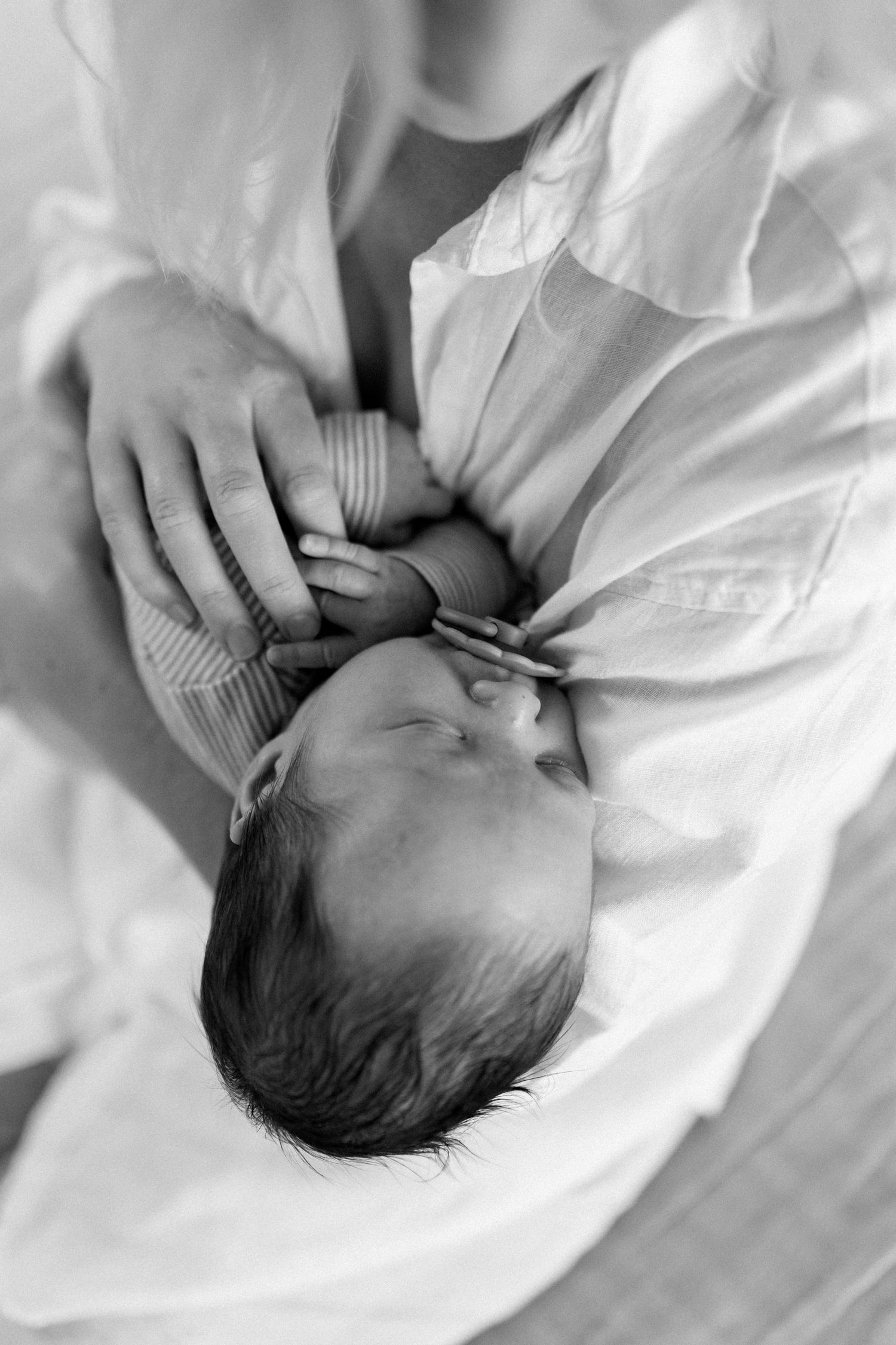 Series of black and white photos showing a peaceful sleeping newborn baby on white sheets.