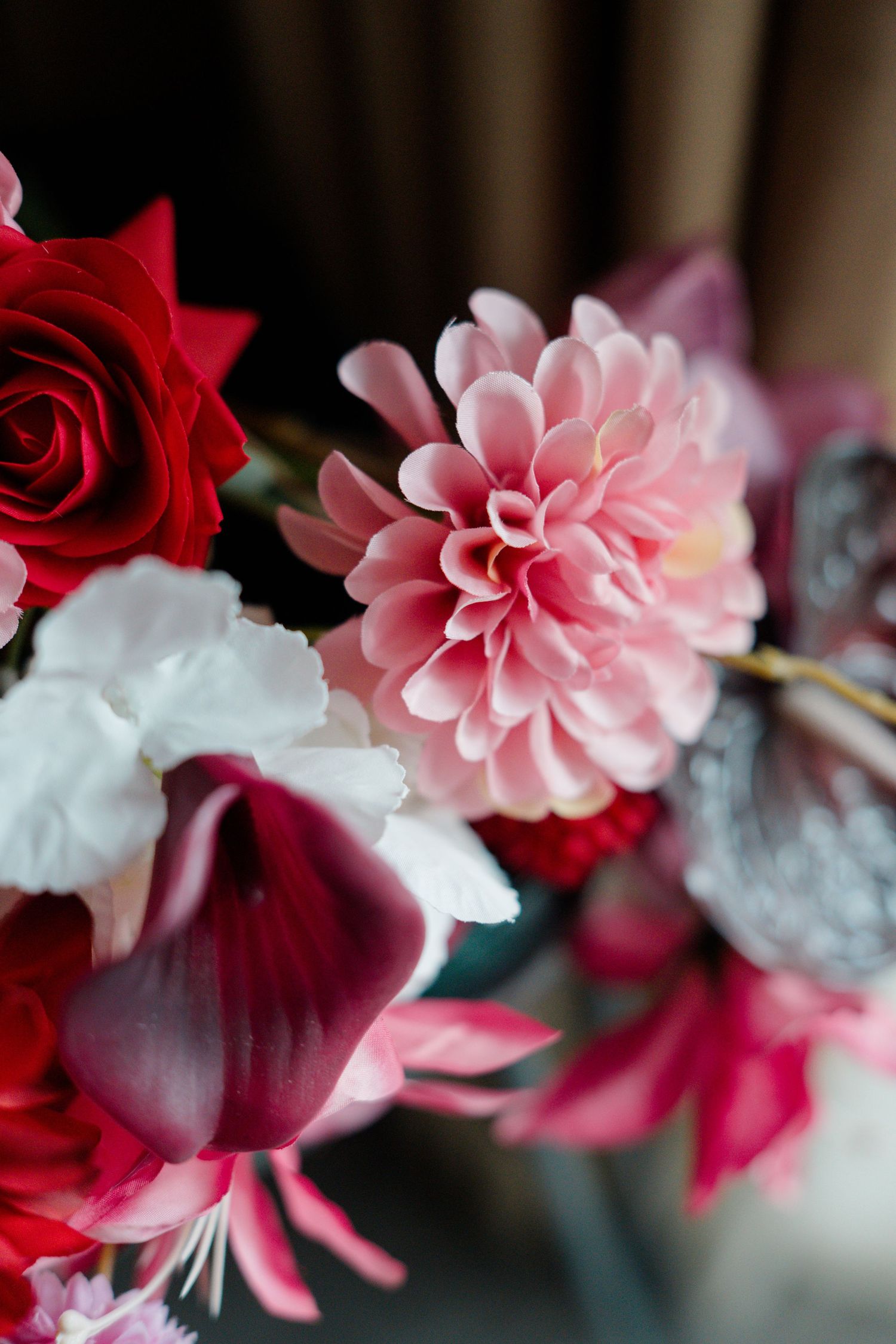 Close-up of a vibrant wedding bouquet featuring pink dahlias, red roses, and white flowers.