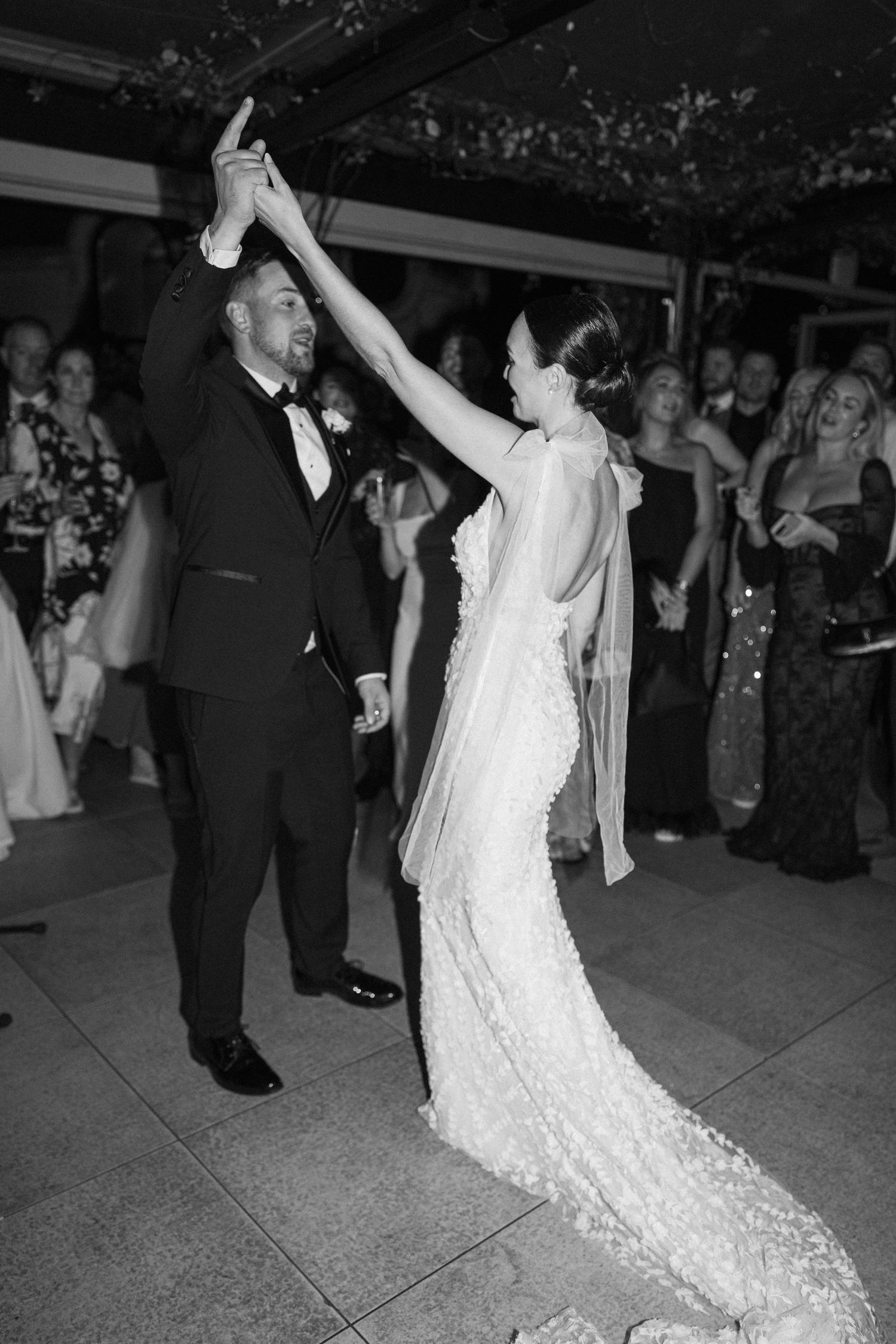 A bride in a flowing lace dress spins gracefully during a wedding dance.