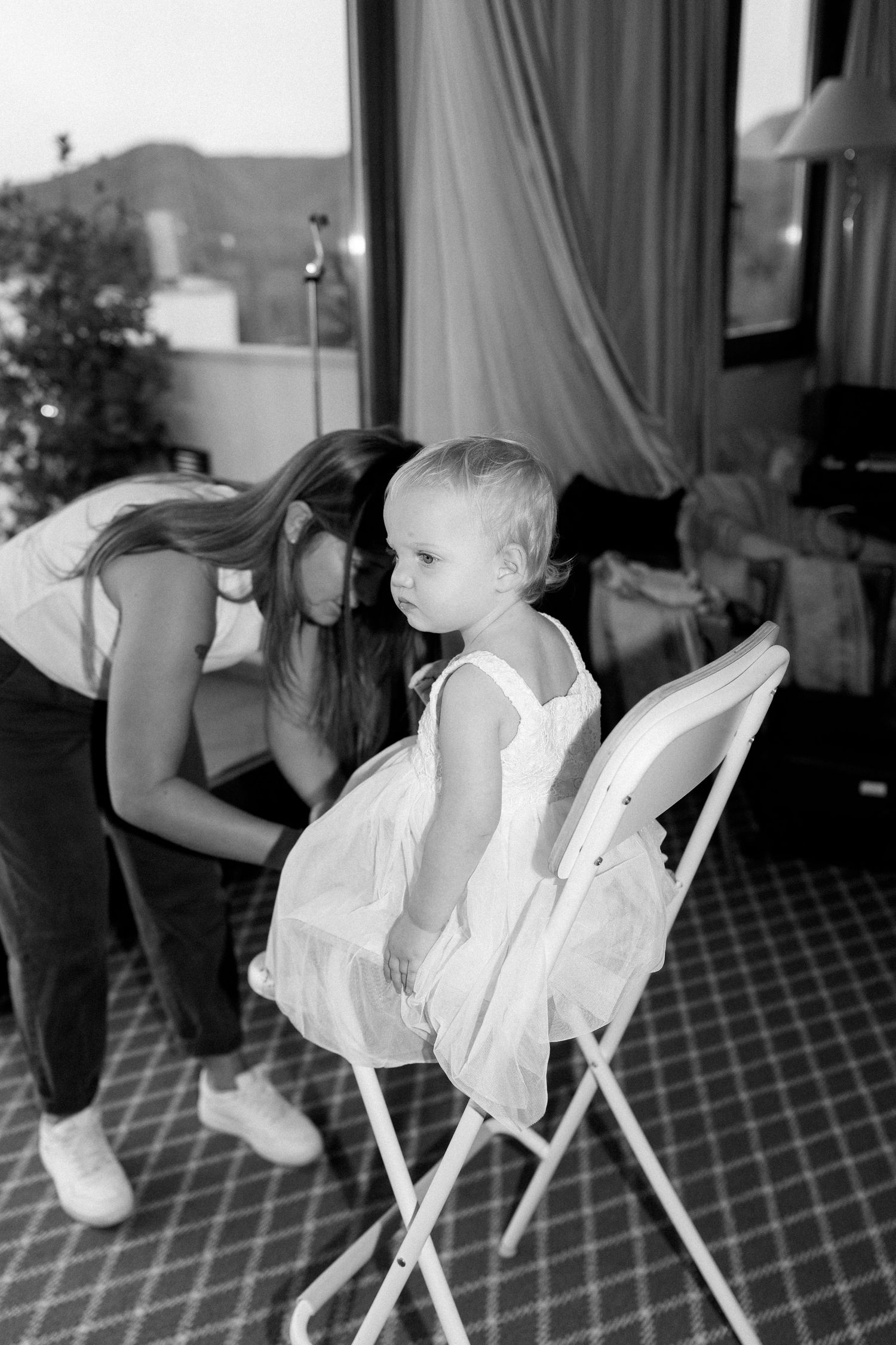 Black and white sequence of a baby sitting in a white dress on a patterned carpet.