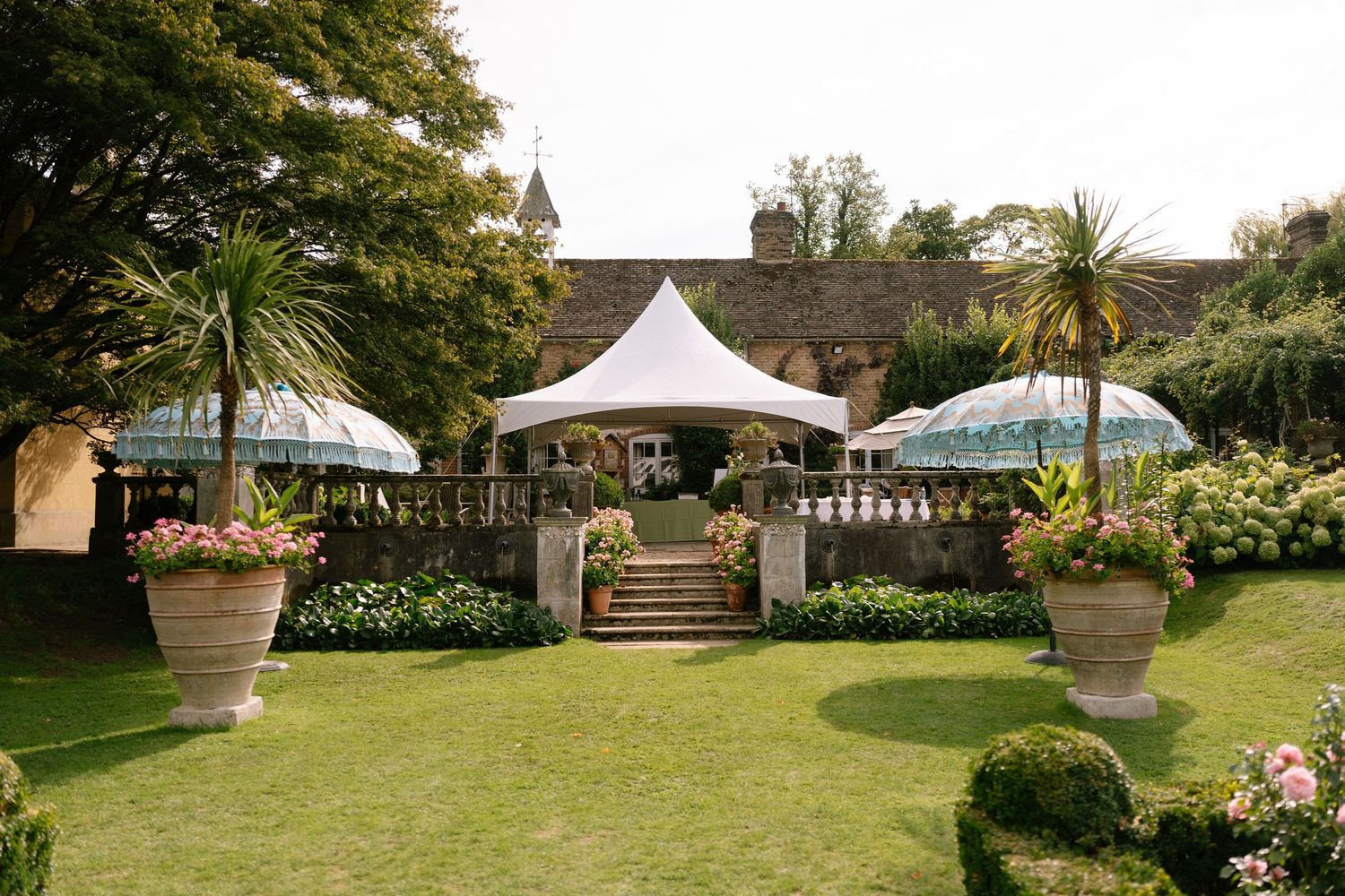 Garden venue with white tents and elegant landscaping for an outdoor event.