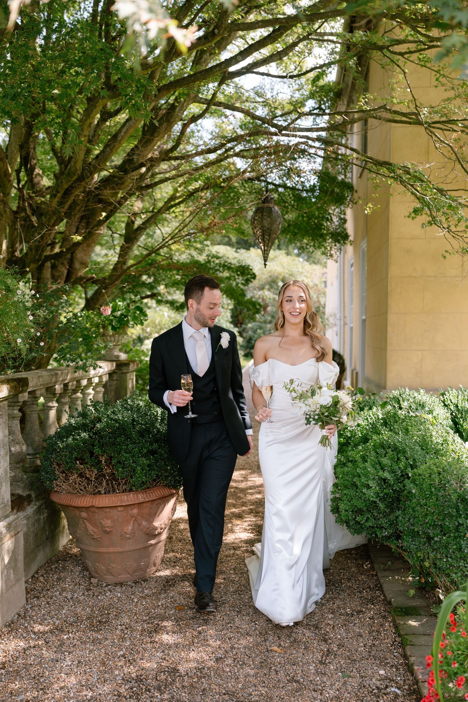 Couple walking through a garden pathway with overhanging trees.