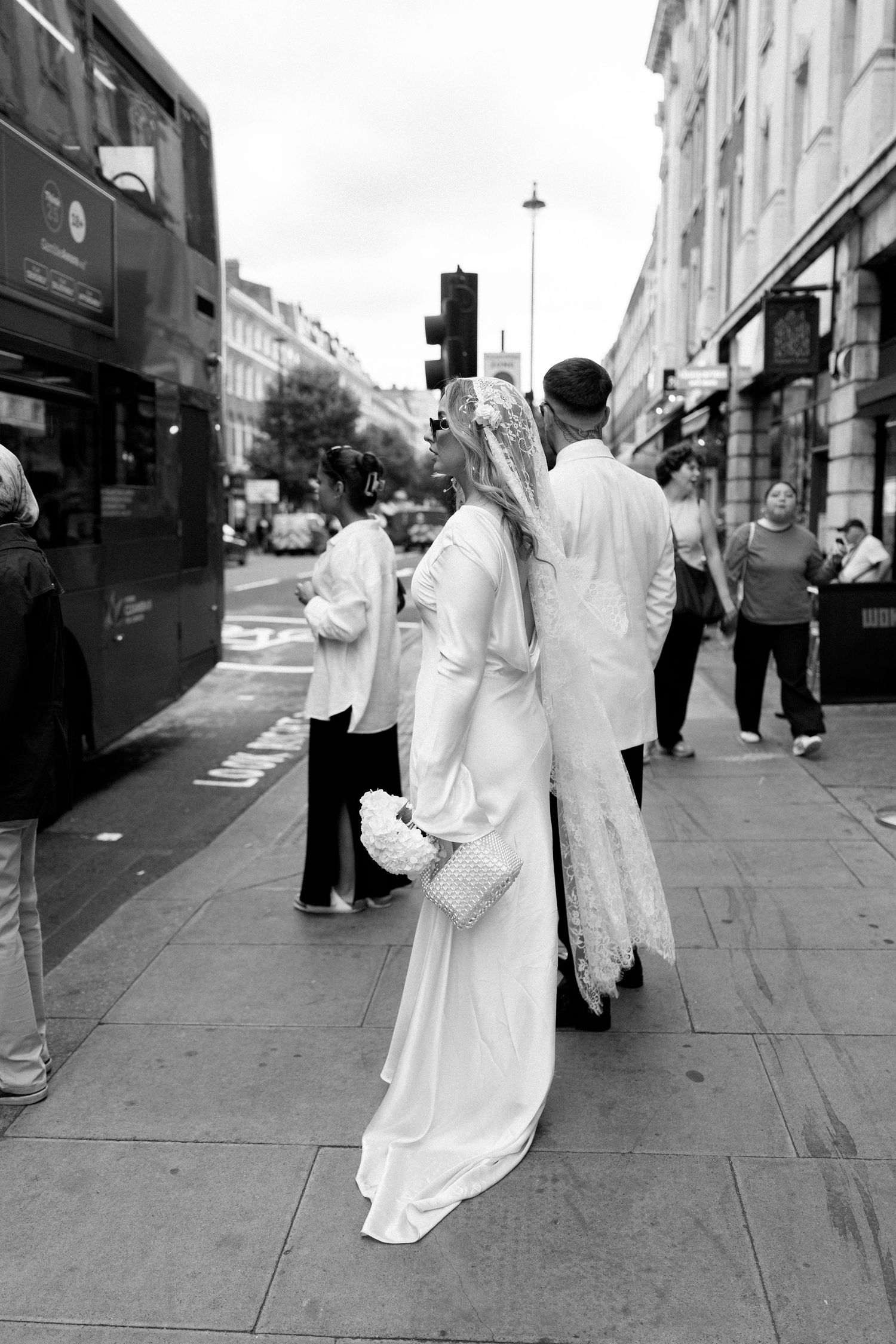 Group wearing flowing white dresses walks down a city street in a dramatic fashion sequence.