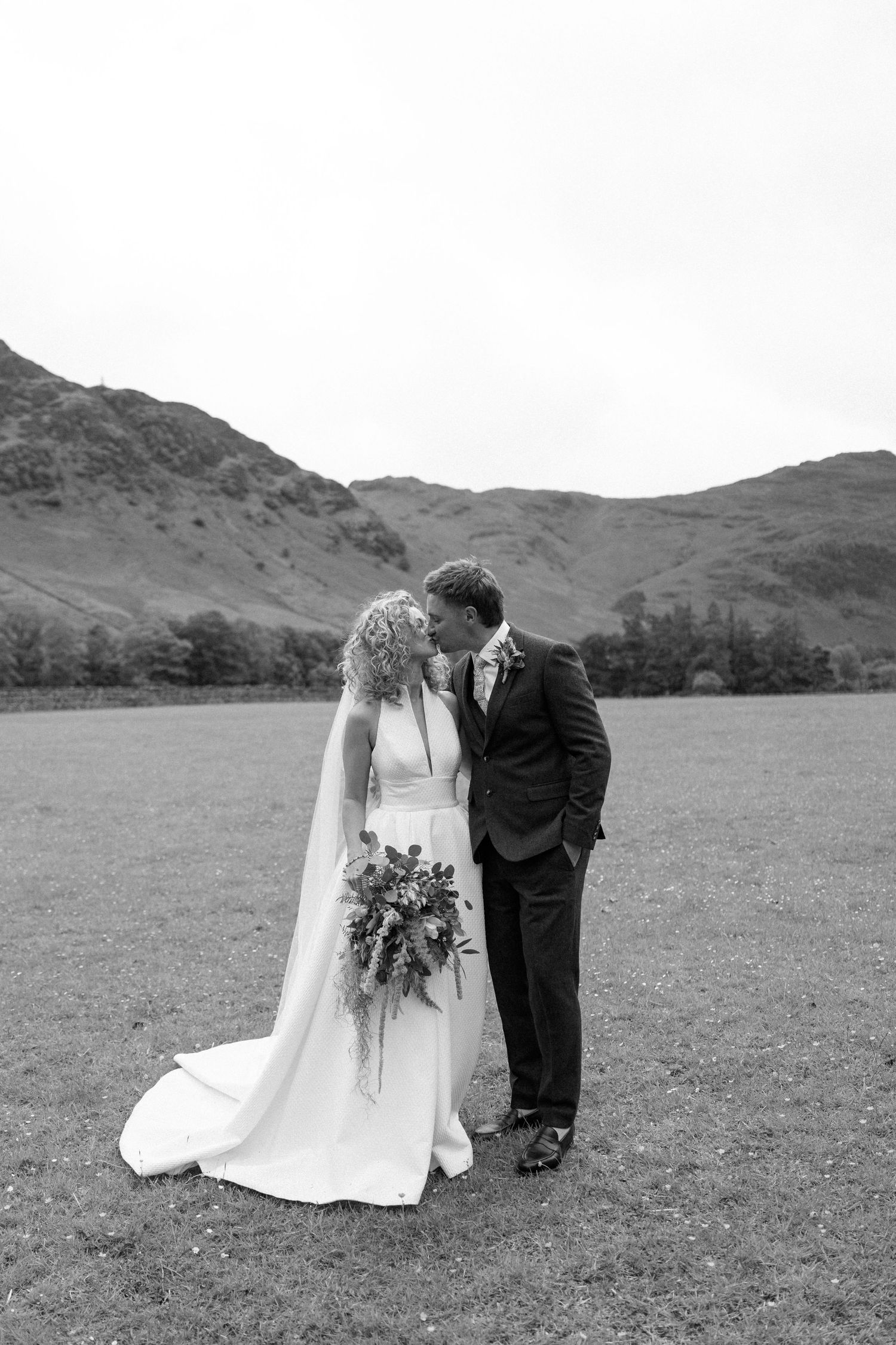 A romantic black and white wedding portrait against a mountainous backdrop in the countryside.