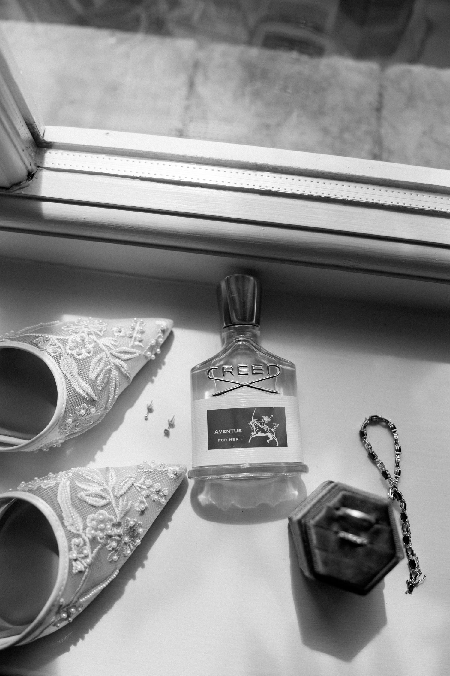 A series of black and white photos showing a pendant necklace with a cross charm hanging from a rearview mirror.