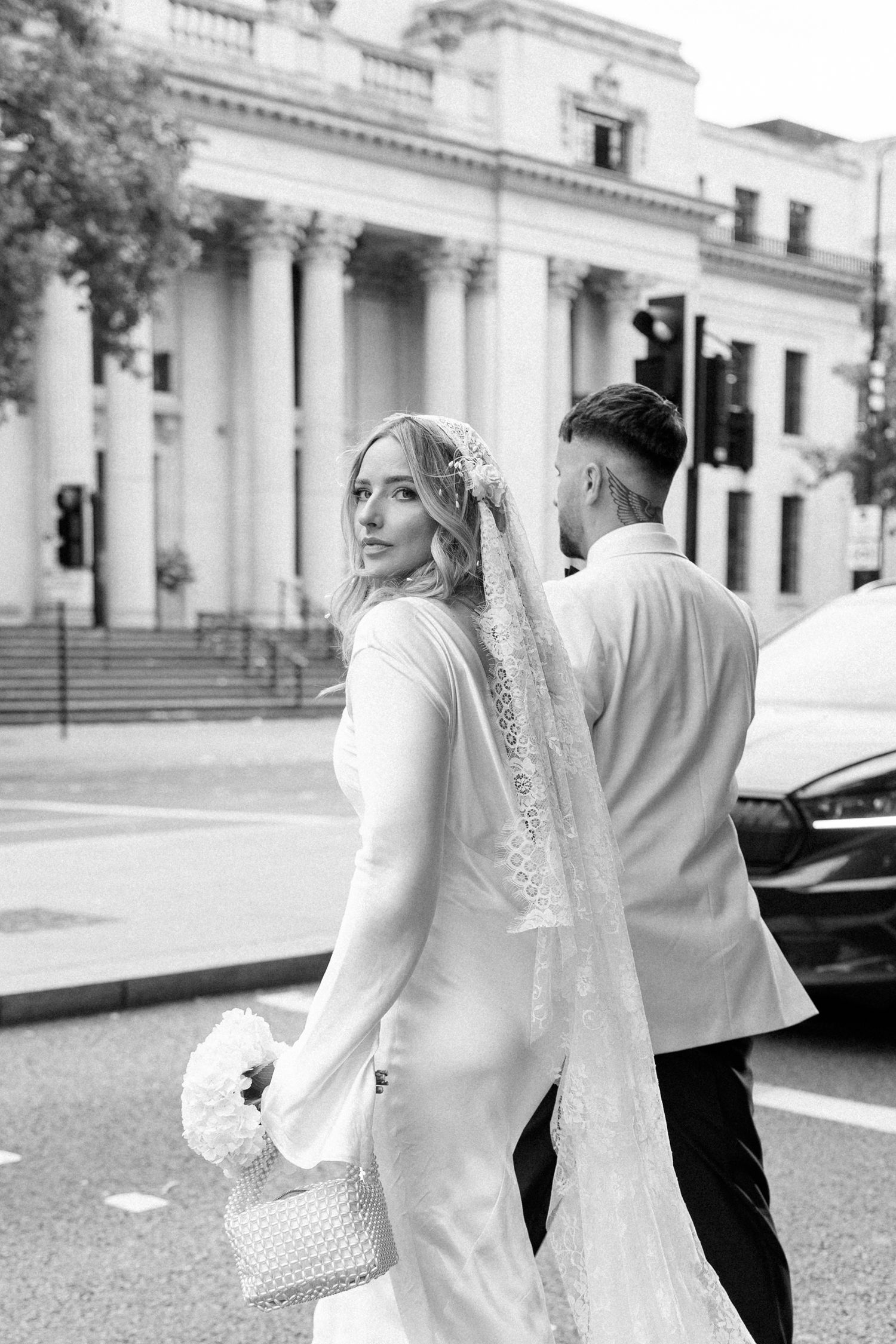 Black and white sequence of newlyweds walking outside a classical building with columns.