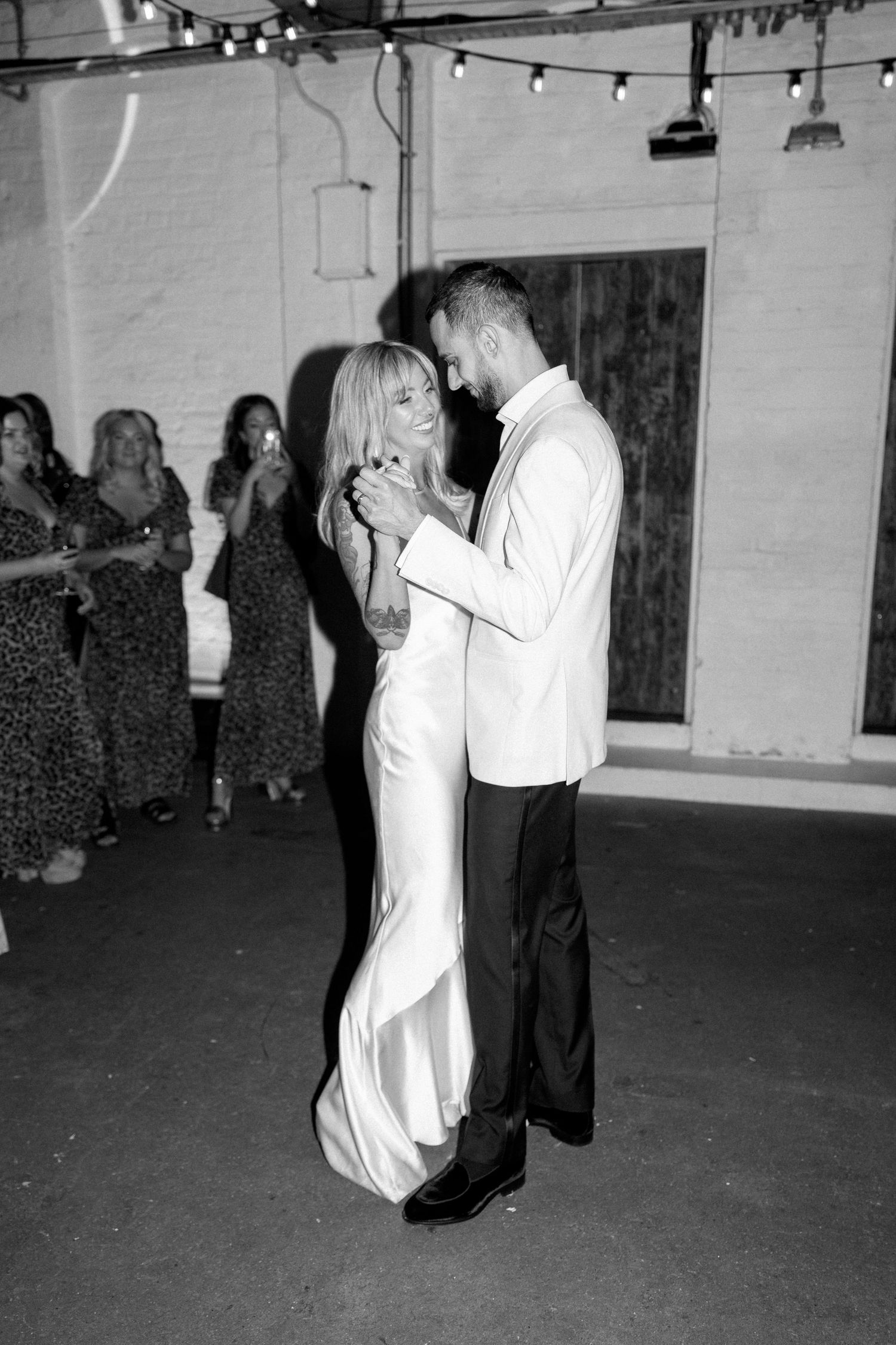 Black and white photos of couples slow dancing at an indoor reception venue.