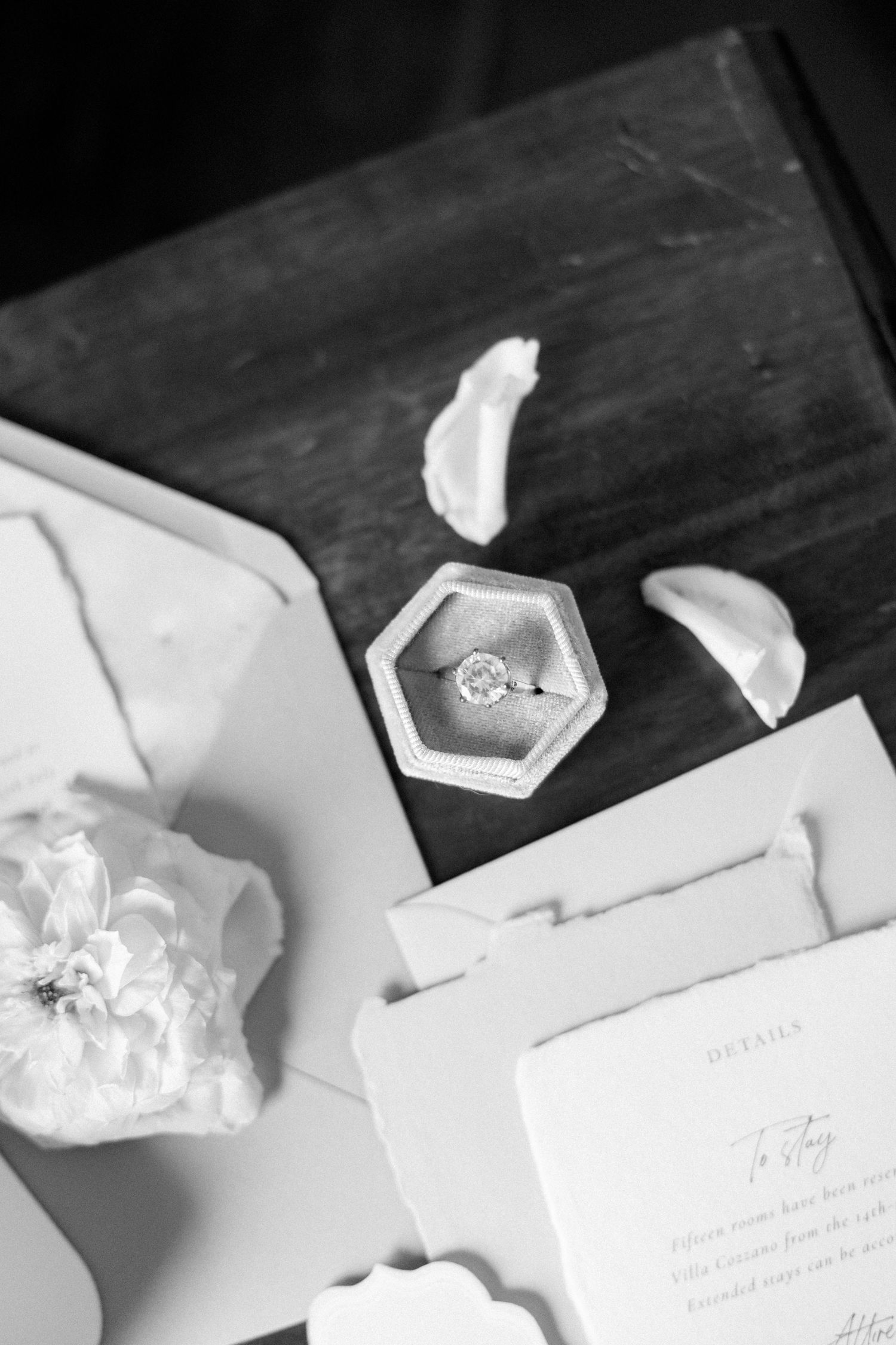 Black and white photo of wedding stationery with hexagonal details on dark surface.